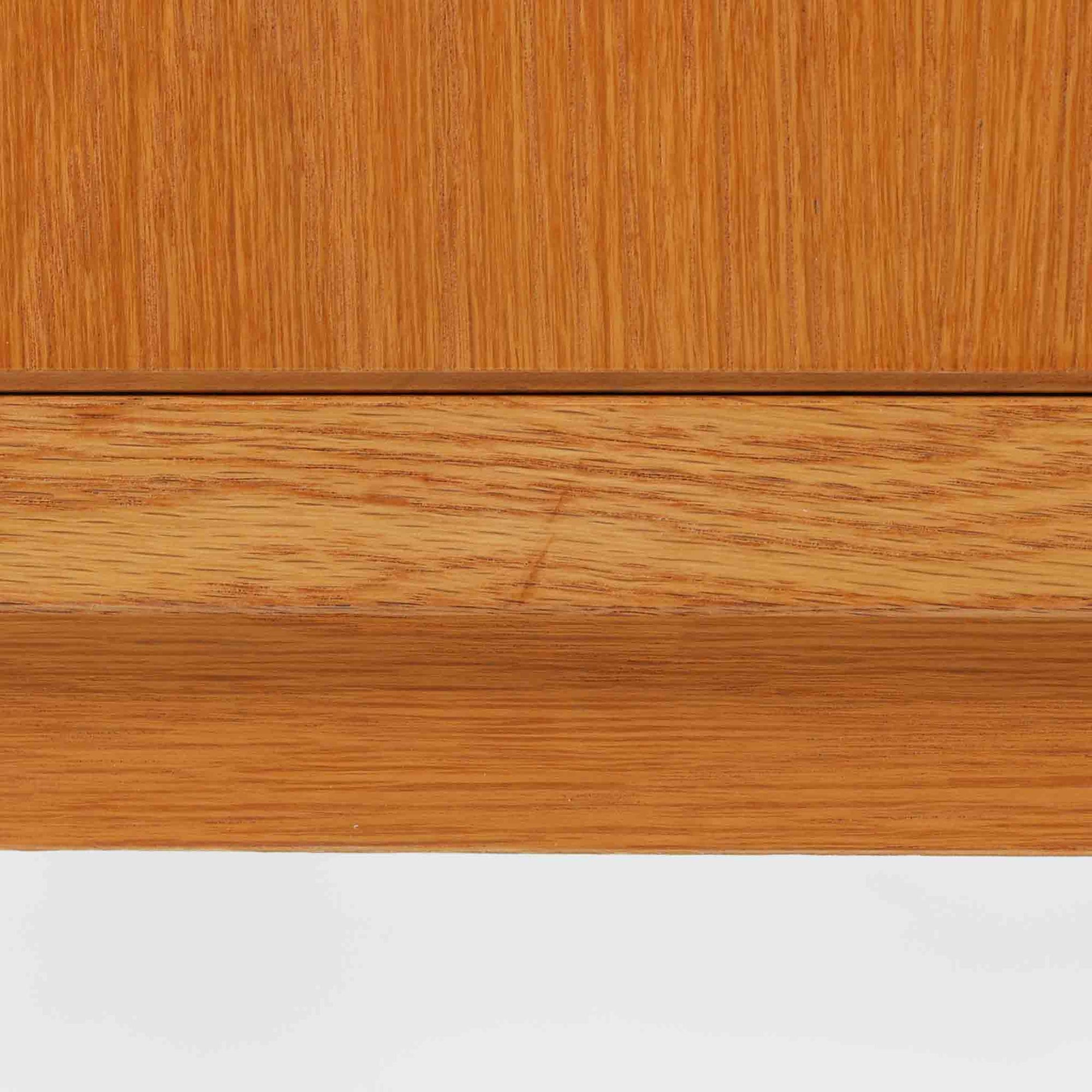 B. FridhagenがBodaforsのために手掛けたディスプレイシェルフは、端正なプロポーションと実用性を兼ね備えたスウェーデン製ビンテージ家具です。上部は抜け感のあるオープン棚構造で、器や書籍、オブジェなどを軽やかに飾ることができ、下部には4段の引き出しを備え、日常使いの収納にも対応します。オーク材ならではの明るく上品な木肌と、直線を基調とした構成が北欧らしい落ち着いた印象を生み、空間をすっきりとまとめてくれます。幅90cm、高さ122cmの小ぶりなサイズ感で、ダイニングやリビング、書斎など幅広いシーンに取り入れやすく、経年変化による木の表情も楽しめる一台です。