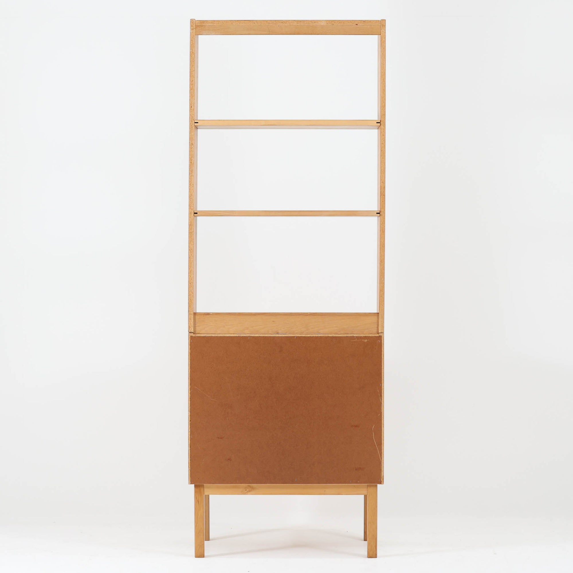 B. Fridhagenがデザインし、Bodafors社により1963年に製作されたスリムシェルフです。オーク材のやわらかな木目と明るい色合いが空間に温もりをもたらし、上部のオープン棚と下部の4段引き出しを備えた実用的な構成が魅力。幅63cmのすっきりとしたサイズで、書斎やリビングの一角にも取り入れやすい一台です。直線的で端正なフォルムと丁寧なつくりから、北欧ビンテージならではの機能美と経年の味わいを感じられる逸品です。