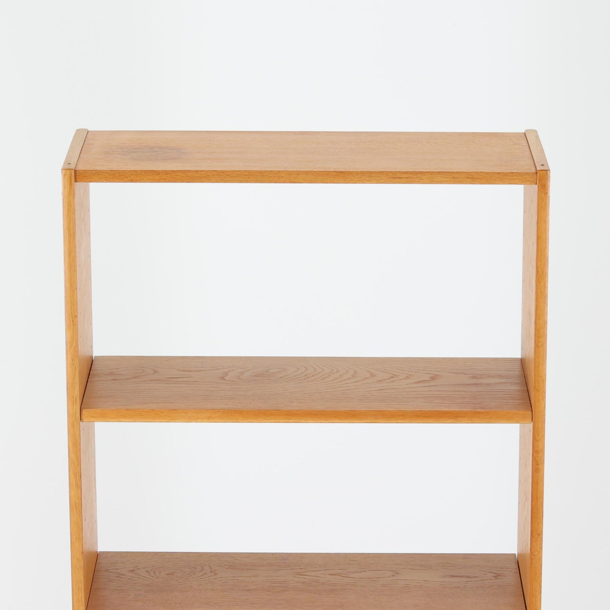 B. Fridhagenがデザインし、Bodafors社により1963年に製作されたスリムシェルフです。オーク材のやわらかな木目と明るい色合いが空間に温もりをもたらし、上部のオープン棚と下部の4段引き出しを備えた実用的な構成が魅力。幅63cmのすっきりとしたサイズで、書斎やリビングの一角にも取り入れやすい一台です。直線的で端正なフォルムと丁寧なつくりから、北欧ビンテージならではの機能美と経年の味わいを感じられる逸品です。