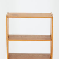 B. Fridhagenがデザインし、Bodafors社により1963年に製作されたスリムシェルフです。オーク材のやわらかな木目と明るい色合いが空間に温もりをもたらし、上部のオープン棚と下部の4段引き出しを備えた実用的な構成が魅力。幅63cmのすっきりとしたサイズで、書斎やリビングの一角にも取り入れやすい一台です。直線的で端正なフォルムと丁寧なつくりから、北欧ビンテージならではの機能美と経年の味わいを感じられる逸品です。