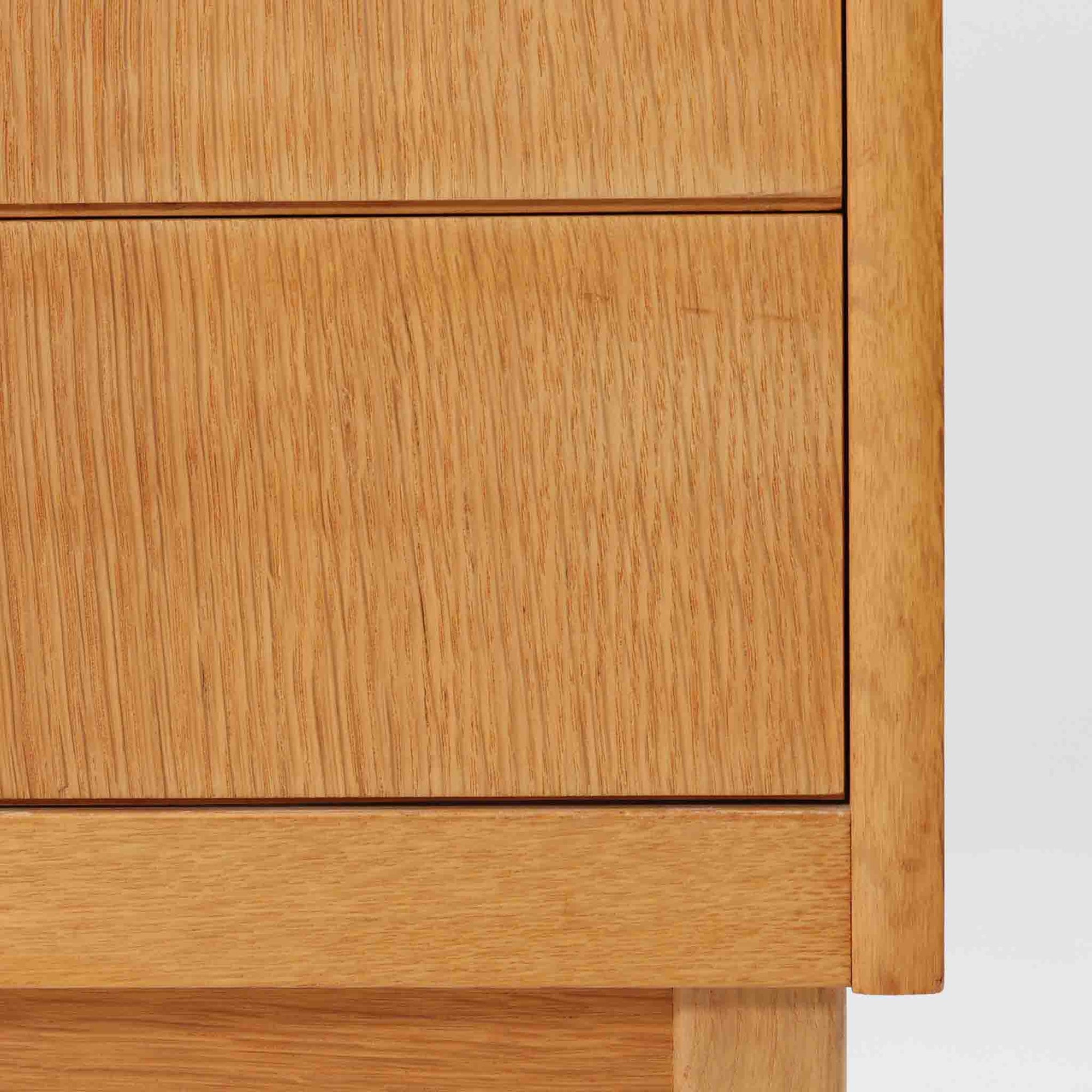 B. Fridhagenがデザインし、Bodafors社により1963年に製作されたスリムシェルフです。オーク材のやわらかな木目と明るい色合いが空間に温もりをもたらし、上部のオープン棚と下部の4段引き出しを備えた実用的な構成が魅力。幅63cmのすっきりとしたサイズで、書斎やリビングの一角にも取り入れやすい一台です。直線的で端正なフォルムと丁寧なつくりから、北欧ビンテージならではの機能美と経年の味わいを感じられる逸品です。