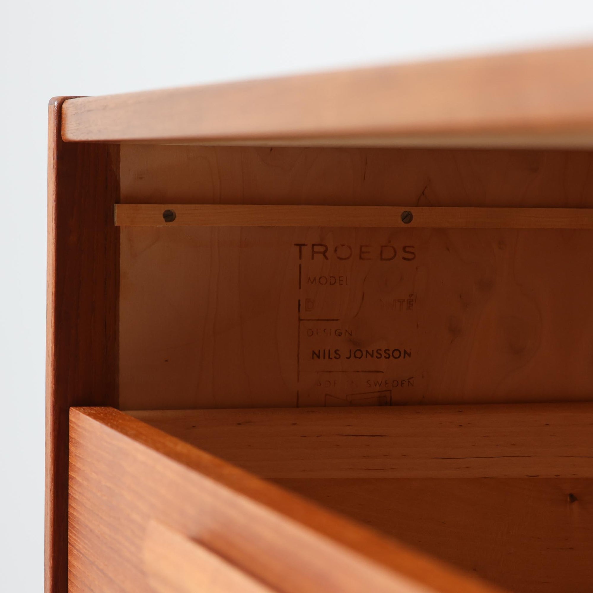 Nils Jonsson（ニールス・ヨンソン）がデザインし、Hugo Troeds（ヒューゴー・トロエッツ）社より製作されたDomi Monteシリーズのスリムシェルフです。良質なチーク材を用いた端正なキャビネットとオープンシェルフを組み合わせた構成で、収納力と見せるディスプレイ性を両立しています。直線を基調とした洗練されたフォルムと、引き出しに刻まれた繊細な手掛けが北欧らしい上品さを演出し、リビングや書斎、ダイニング収納としても活躍します。経年変化によって深みを増した木肌から、当時の職人技とビンテージならではの存在感が感じられる一台です。