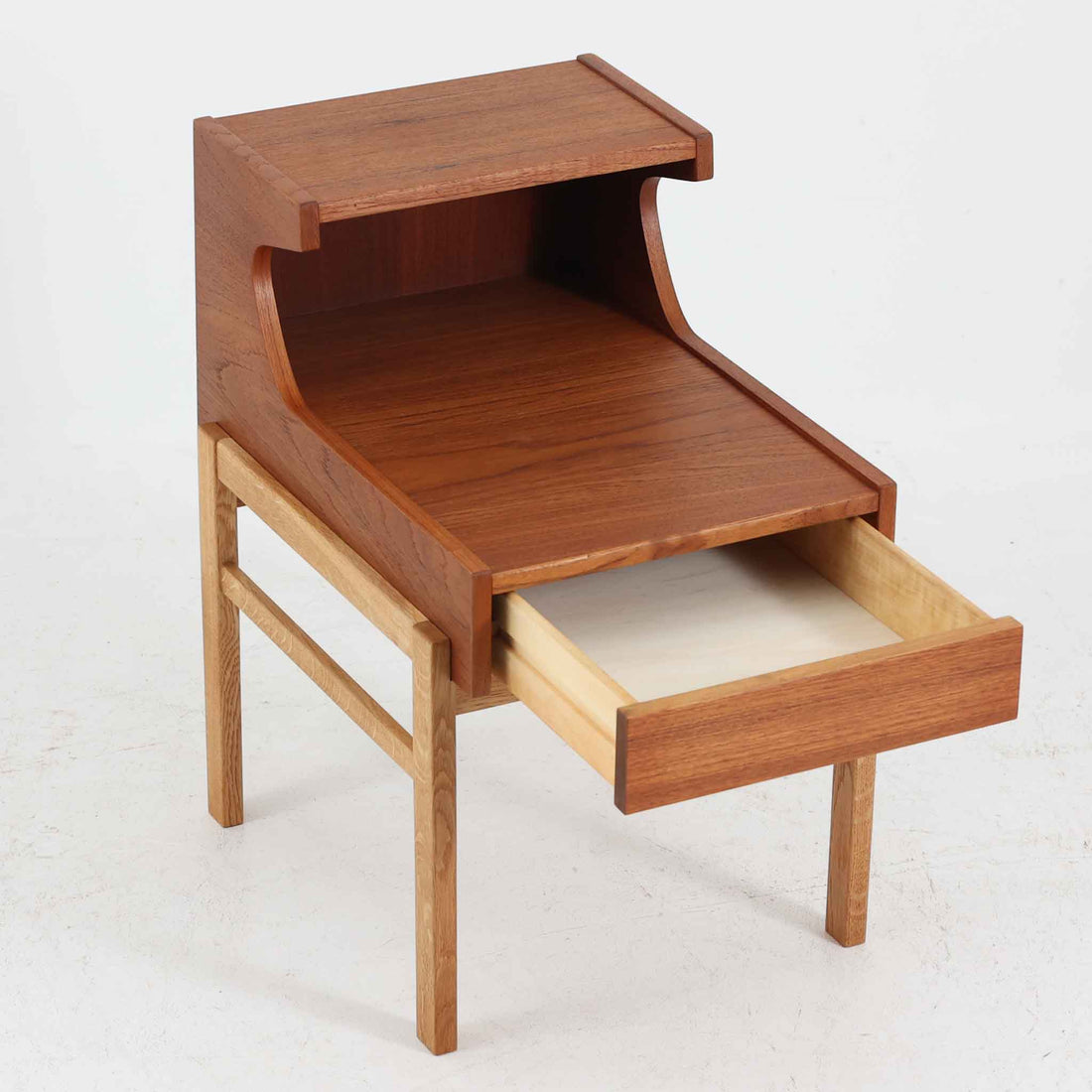 スウェーデンのGustavssons Mobelfabrik社製によるサイドチェストです。チーク材とオーク材を組み合わせたデザインで、温かみのある色合いと素材のコントラストが美しい一台です。奥行きが広く設計されており、天板スペースには照明や小物を置くことができます。緩やかなカーブを描く側面や細身の脚部が軽やかな印象を与え、寝室のナイトテーブルやリビングの補助台としても活躍します。北欧らしい洗練された職人技が光るビンテージ家具です。