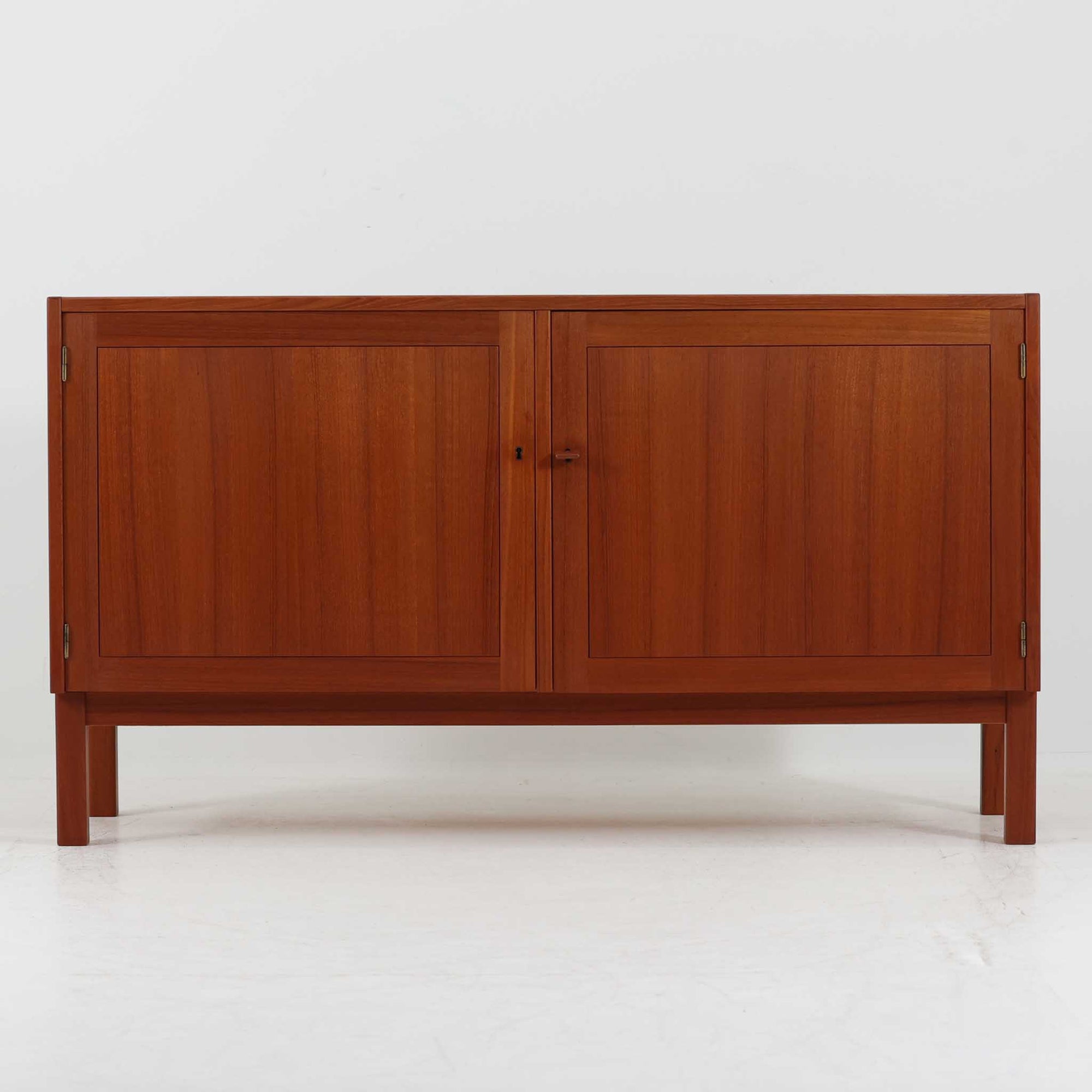 Nils JonssonがTroedsのためにデザインした「Domi Monte」モデルのキャビネットは、チーク材の豊かな木目と端正な框扉が魅力の北欧ビンテージ家具で、内部には可動棚を備えた左右対称の収納スペースが広がり食器や書類、小物類をすっきりと整理でき、チーク材をジョイントした鍵が細部の意匠性を高めつつ、直線的でシンプルな構造に細身の脚部を組み合わせることで軽やかな印象を生み出し、1960年代スウェーデン家具らしい上質で実用性の高いデザインが空間に落ち着いた存在感を添え、経年で深まった木肌の美しさも相まってリビングやダイニングのサイド収納として幅広く活躍する一台です。