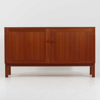 Nils JonssonがTroedsのためにデザインした「Domi Monte」モデルのキャビネットは、チーク材の豊かな木目と端正な框扉が魅力の北欧ビンテージ家具で、内部には可動棚を備えた左右対称の収納スペースが広がり食器や書類、小物類をすっきりと整理でき、チーク材をジョイントした鍵が細部の意匠性を高めつつ、直線的でシンプルな構造に細身の脚部を組み合わせることで軽やかな印象を生み出し、1960年代スウェーデン家具らしい上質で実用性の高いデザインが空間に落ち着いた存在感を添え、経年で深まった木肌の美しさも相まってリビングやダイニングのサイド収納として幅広く活躍する一台です。