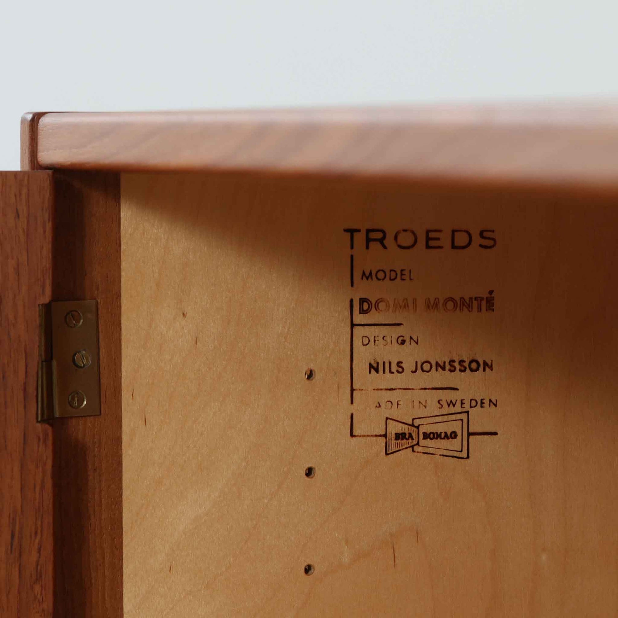 Nils JonssonがTroedsのためにデザインした「Domi Monte」モデルのキャビネットは、チーク材の豊かな木目と端正な框扉が魅力の北欧ビンテージ家具で、内部には可動棚を備えた左右対称の収納スペースが広がり食器や書類、小物類をすっきりと整理でき、チーク材をジョイントした鍵が細部の意匠性を高めつつ、直線的でシンプルな構造に細身の脚部を組み合わせることで軽やかな印象を生み出し、1960年代スウェーデン家具らしい上質で実用性の高いデザインが空間に落ち着いた存在感を添え、経年で深まった木肌の美しさも相まってリビングやダイニングのサイド収納として幅広く活躍する一台です。