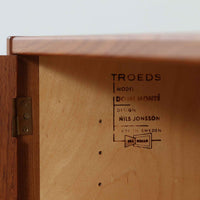 Nils JonssonがTroedsのためにデザインした「Domi Monte」モデルのキャビネットは、チーク材の豊かな木目と端正な框扉が魅力の北欧ビンテージ家具で、内部には可動棚を備えた左右対称の収納スペースが広がり食器や書類、小物類をすっきりと整理でき、チーク材をジョイントした鍵が細部の意匠性を高めつつ、直線的でシンプルな構造に細身の脚部を組み合わせることで軽やかな印象を生み出し、1960年代スウェーデン家具らしい上質で実用性の高いデザインが空間に落ち着いた存在感を添え、経年で深まった木肌の美しさも相まってリビングやダイニングのサイド収納として幅広く活躍する一台です。