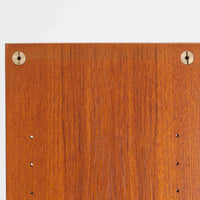 B.フリードホーゲンがデザインし、Bodafors社により製作された北欧ビンテージのディスプレイシェルフです。チーク材の美しい木目を活かした縦に伸びる端正なフレーム構成が印象的で、オープン棚と下部収納を組み合わせた実用性の高いデザインとなっています。上段は抜け感のある棚板構造で、書籍や器、オブジェを軽やかに飾ることができ、下段の引き戸収納は生活感の出やすい物をすっきりと収められます。脚付きによる軽快な佇まいと、経年変化によって深みを増した素材感が、空間に北欧ビンテージならではの落ち着いた存在感を与えます。