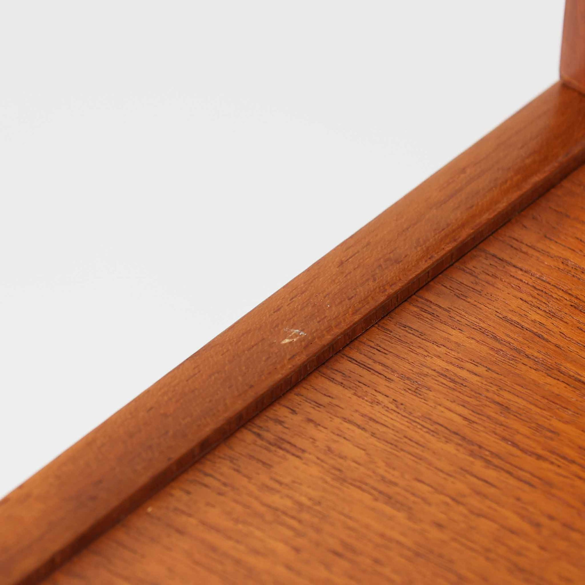 B.フリードホーゲンがデザインし、Bodafors社により製作された北欧ビンテージのディスプレイシェルフです。チーク材の美しい木目を活かした縦に伸びる端正なフレーム構成が印象的で、オープン棚と下部収納を組み合わせた実用性の高いデザインとなっています。上段は抜け感のある棚板構造で、書籍や器、オブジェを軽やかに飾ることができ、下段の引き戸収納は生活感の出やすい物をすっきりと収められます。脚付きによる軽快な佇まいと、経年変化によって深みを増した素材感が、空間に北欧ビンテージならではの落ち着いた存在感を与えます。