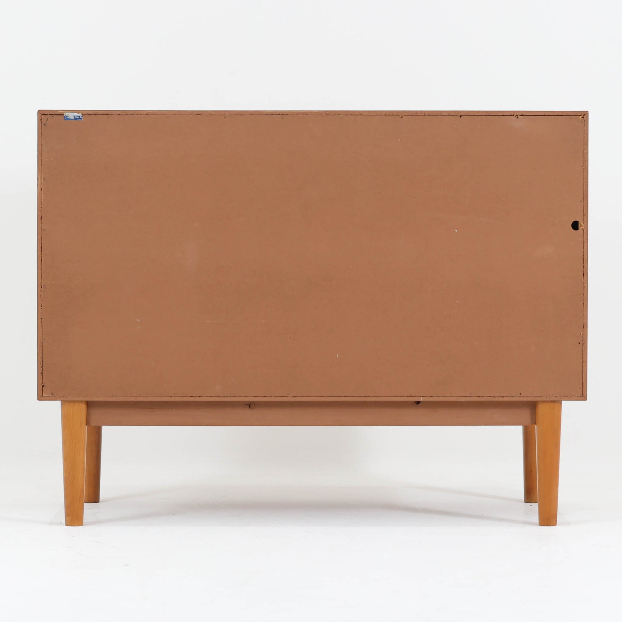 Nils Jonssonがデザインし、Hugo Troedsが製作した幅95cmの小ぶりなボードです。上質なチーク材を用いた端正な箱型フォルムに、楕円形の彫り込み取っ手がさりげないアクセントを添えています。引き戸仕様により限られた空間でも扱いやすく、内部には棚板を備え収納力も十分。すらりと伸びる脚部が軽やかな印象を与え、リビングや書斎、玄関先でも活躍します。経年により深みを増した木肌が北欧ビンテージならではの温もりと存在感を感じさせる一品です。