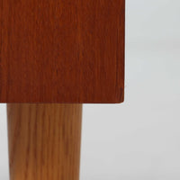 こちらのディスプレイシェルフは、チーク材とオーク材を組み合わせた柔らかなコントラストが魅力の北欧ビンテージ家具で、上部には奥行きの浅い棚板を2段備えた軽やかなディスプレイスペースに加えて天板部には引き棚が設けられており、雑貨や植物、本のレイアウトを楽しみながら作業スペースとしても活用でき、下部のスライド扉収納によって見せる収納と隠す収納を両立できるほか、細身の脚部が全体に浮遊感を与えて空間を圧迫しないバランスの良いデザインに仕上がっており、経年で深まった木肌の温もりも相まってリビングやダイニング、玄関周りにも取り入れやすい一台です。