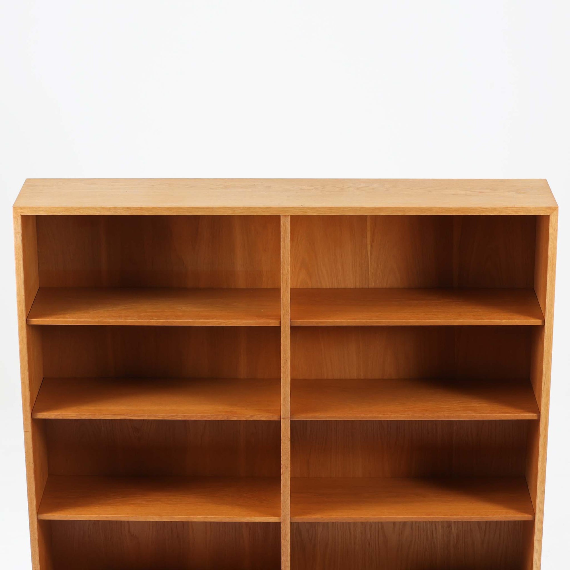 Borge Mogensenがデザインし、Karl Andersson &amp; Sonerが製作した幅135cmのブックシェルフです。上質なオーク材を用いた無駄のない直線的な構成が特徴で、中央の仕切りにより整然とした収納を実現しています。固定棚による堅牢な構造は、日常使いの書籍や資料をしっかりと支え、空間に落ち着いた存在感をもたらします。素材の質感を活かした端正な佇まいは、リビングや書斎、オフィスにも自然に馴染み、北欧ビンテージならではの実直な美しさと経年変化の魅力を感じられる一品です。