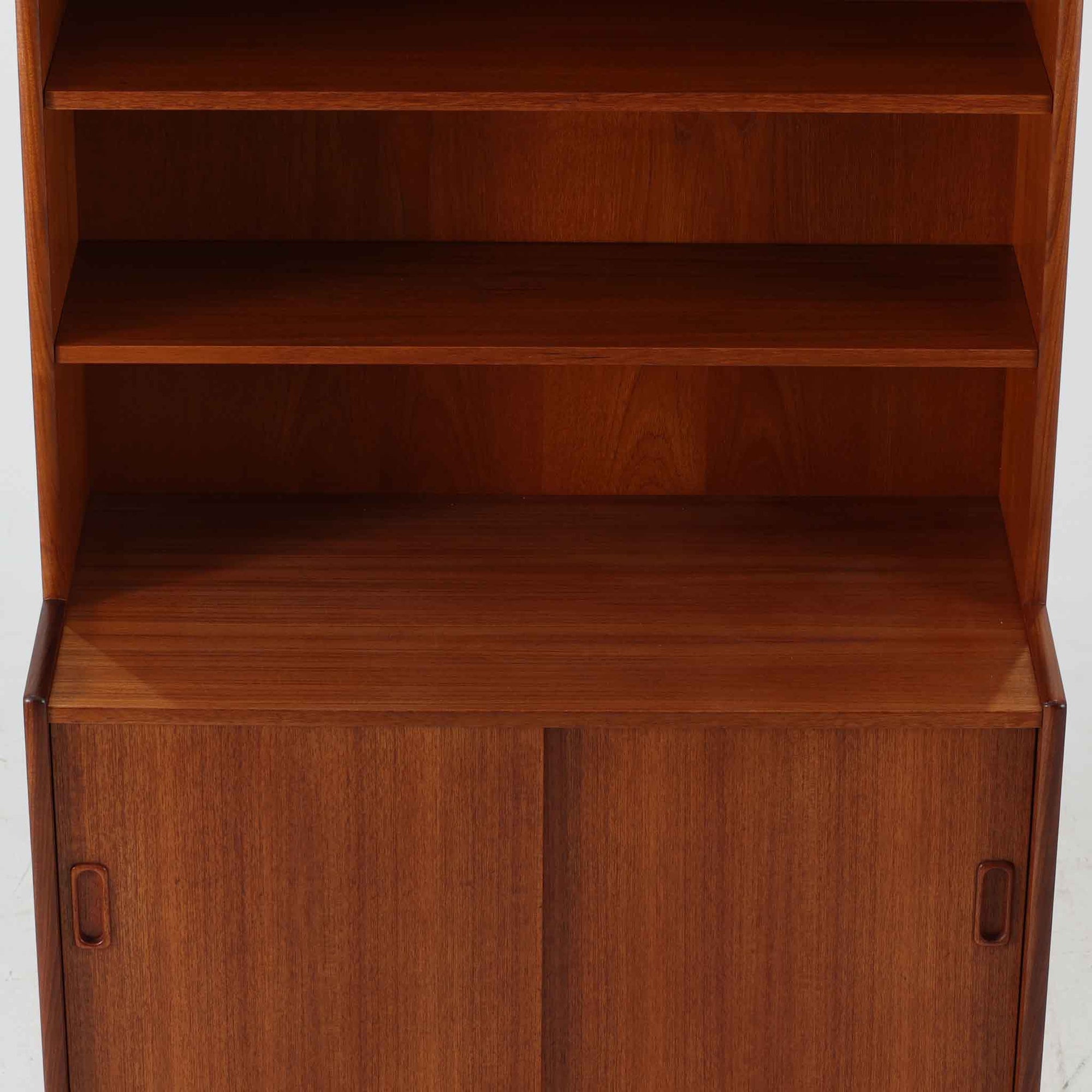 スウェーデン製のこちらのディスプレイシェルフは、チーク材の深みある木目が美しい上段のオープン棚と、下段のスライド扉収納を組み合わせた機能性の高い構成が特徴で、細身のフレームや角を丁寧に面取りした滑らかなフォルムが空間に柔らかな印象をもたらす北欧ビンテージ家具です。書籍や雑貨を見せながら収納でき、下段には日用品をすっきりと隠してしまえるため、リビングやダイニングの整理にも便利で、経年によって深まったチーク材の風合いがインテリアに温かみと落ち着きを添える一台です。