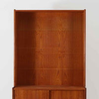 スウェーデン製のこちらのディスプレイシェルフは、チーク材の深みある木目が美しい上段のオープン棚と、下段のスライド扉収納を組み合わせた機能性の高い構成が特徴で、細身のフレームや角を丁寧に面取りした滑らかなフォルムが空間に柔らかな印象をもたらす北欧ビンテージ家具です。書籍や雑貨を見せながら収納でき、下段には日用品をすっきりと隠してしまえるため、リビングやダイニングの整理にも便利で、経年によって深まったチーク材の風合いがインテリアに温かみと落ち着きを添える一台です。