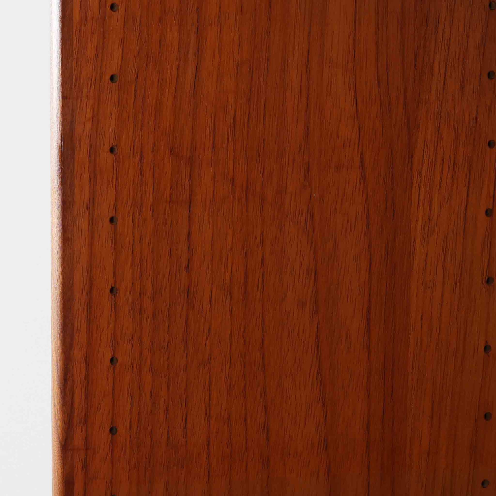 スウェーデン製のこちらのディスプレイシェルフは、チーク材の深みある木目が美しい上段のオープン棚と、下段のスライド扉収納を組み合わせた機能性の高い構成が特徴で、細身のフレームや角を丁寧に面取りした滑らかなフォルムが空間に柔らかな印象をもたらす北欧ビンテージ家具です。書籍や雑貨を見せながら収納でき、下段には日用品をすっきりと隠してしまえるため、リビングやダイニングの整理にも便利で、経年によって深まったチーク材の風合いがインテリアに温かみと落ち着きを添える一台です。