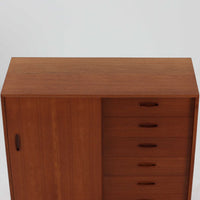 Nils Jonssonがデザインし、Hugo Troedsより発表されたモデルDomi 13のディスプレイシェルフです。チーク材の美しい木目と温かみのある色合いが空間に上質な北欧らしさをもたらします。上段・中段・下段のセクション構造で、それぞれを分けて使用できる柔軟な設計も魅力。下段は右側に引き出し、左側に高さ調整可能な棚を備え、実用性にも優れています。削り出しの取っ手や端正なフレームラインに職人技が感じられ、経年により深みを増した風合いがビンテージならではの存在感を放つ一品です。