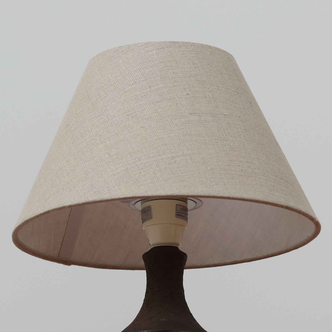 Chris HaslevがJetiのために手掛けたこちらのテーブルランプは、太陽を思わせるレリーフ模様をまとった陶器ベースと、素朴な土肌と釉薬の濃淡が織りなす豊かな表情が魅力で、コンパクトながら存在感を放つ北欧ビンテージ品です。上部のマットな質感が造形を引き締め、リネンシェード越しに広がるあたたかな灯りが空間をやさしく包み込み、リビングやベッドサイドのアクセントとして取り入れやすい一台に仕上がっています。