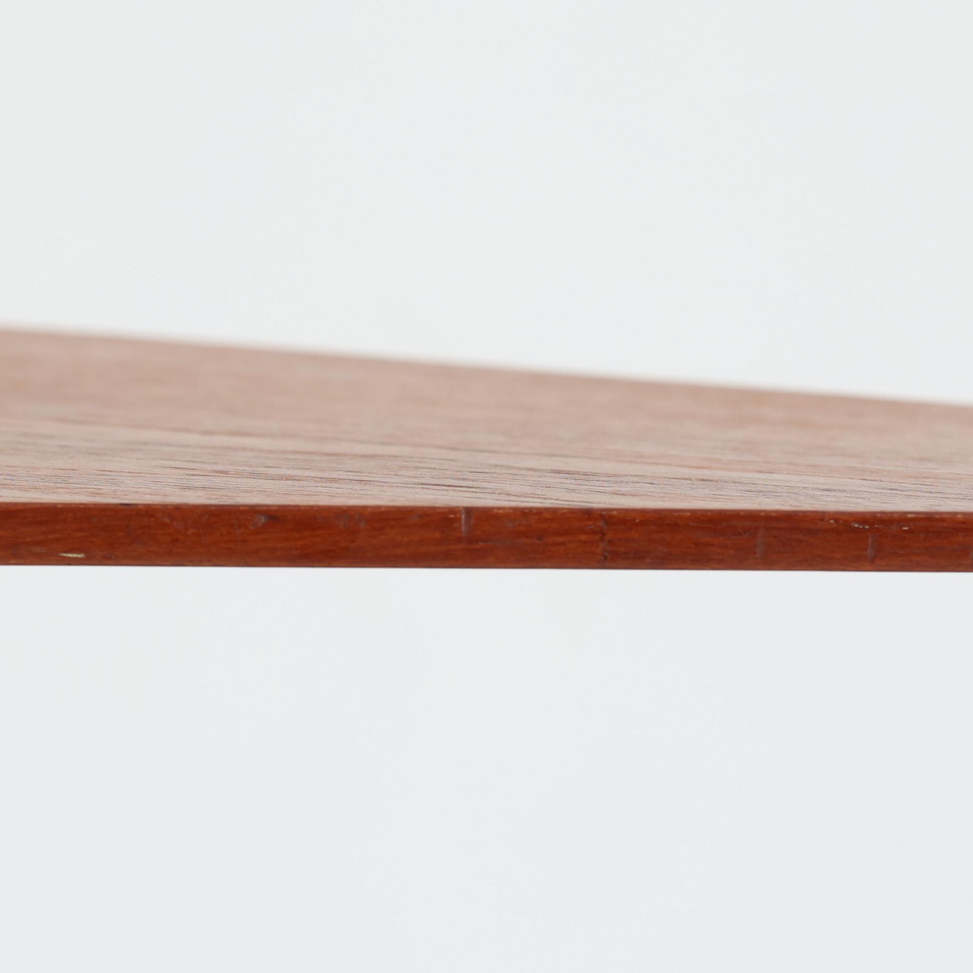 デンマーク製のチーク材サイドテーブルです。三角形に近い柔らかな曲線を描く天板と、すらりと伸びた3本脚が印象的なデザインで、ミッドセンチュリーらしい軽快な佇まいが魅力です。職人による丁寧な削り出しが際立ち、チーク材特有の深みある色合いと滑らかな手触りが楽しめます。コンパクトながら存在感があり、ソファ横やベッドサイドの小物置きとしても最適な一台です。