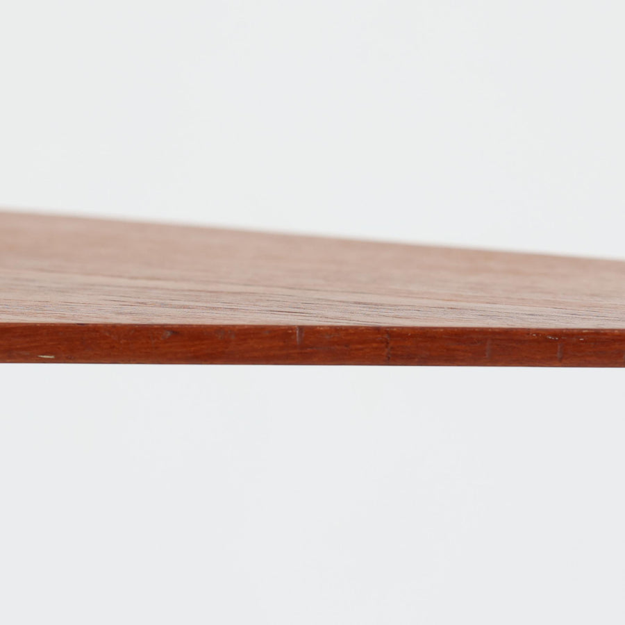 デンマーク製のチーク材サイドテーブルです。三角形に近い柔らかな曲線を描く天板と、すらりと伸びた3本脚が印象的なデザインで、ミッドセンチュリーらしい軽快な佇まいが魅力です。職人による丁寧な削り出しが際立ち、チーク材特有の深みある色合いと滑らかな手触りが楽しめます。コンパクトながら存在感があり、ソファ横やベッドサイドの小物置きとしても最適な一台です。