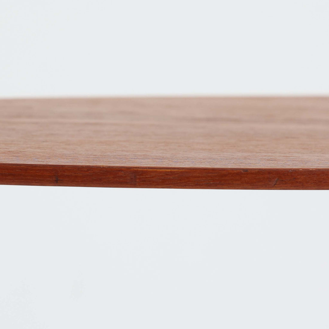 デンマーク製のチーク材サイドテーブルです。三角形に近い柔らかな曲線を描く天板と、すらりと伸びた3本脚が印象的なデザインで、ミッドセンチュリーらしい軽快な佇まいが魅力です。職人による丁寧な削り出しが際立ち、チーク材特有の深みある色合いと滑らかな手触りが楽しめます。コンパクトながら存在感があり、ソファ横やベッドサイドの小物置きとしても最適な一台です。