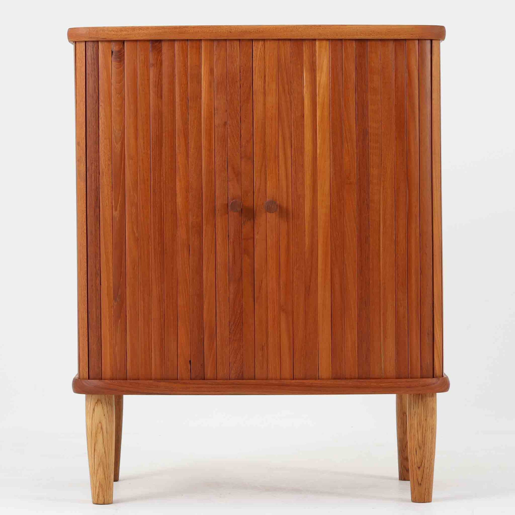 デンマーク製蛇腹キャビネット。チーク材の深みある木肌を活かした美しい縦桟の蛇腹扉が印象的で、開閉の所作そのものに北欧ビンテージらしい職人技を感じられる一台です。丸みを持たせた天板と台輪、軽やかな脚部のバランスが美しく、幅54cmのコンパクトなサイズ感でリビングや書斎、ベッドサイドにも取り入れやすい設計。内部は棚板付きで書類や日用品、小物をすっきり収納でき、見せたくない生活感を美しく隠しながら空間に上質な温もりを添えてくれます。