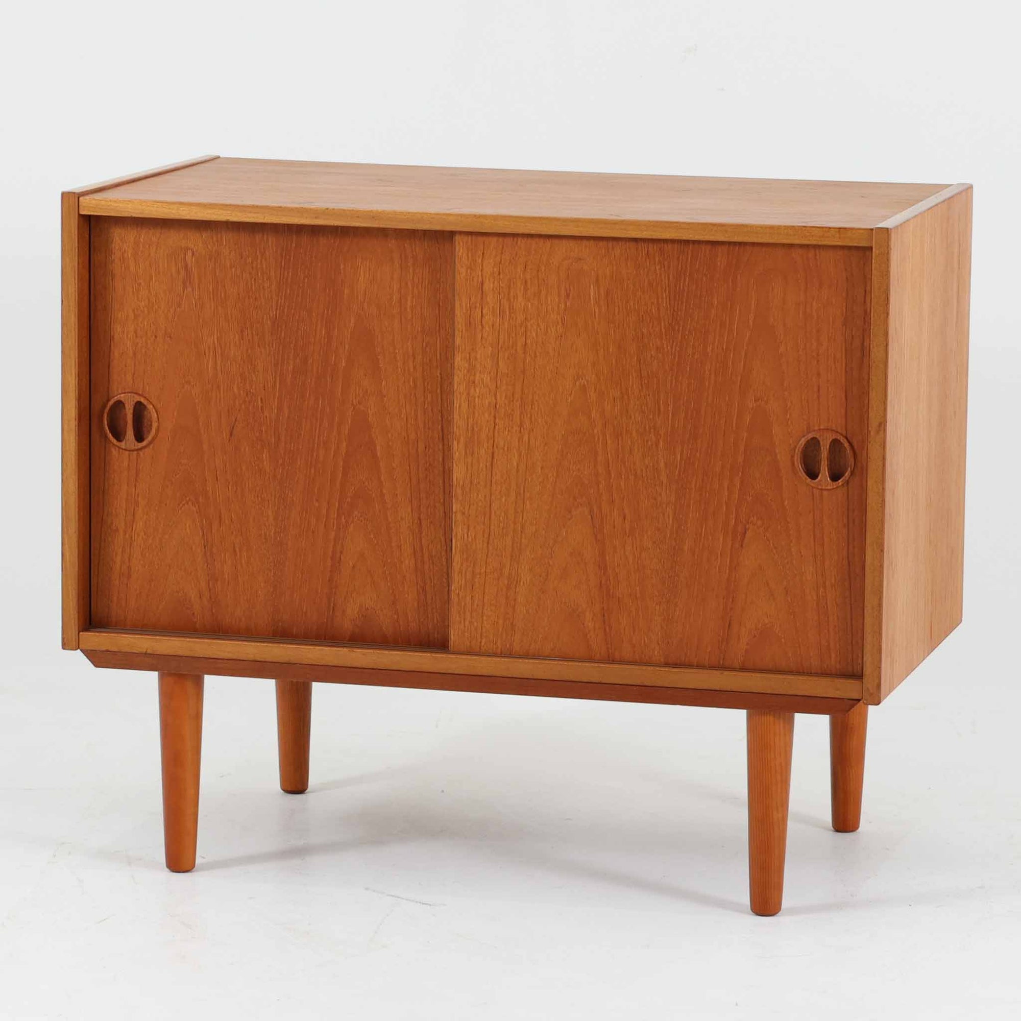 デンマーク製ボードです。チーク材の美しい木目と経年によって深みを増した色艶が魅力で、シンプルな箱型フォルムに丸みを帯びた取手がさりげないアクセントとなっています。引き戸仕様により限られたスペースでも使いやすく、内部には棚板を備え収納力と実用性を兼備。すっきりとした脚部が軽やかな印象を与え、リビングやダイニングで上質な収納家具として活躍する一台です。ビンテージならではの風合いと丁寧な作りが感じられます。