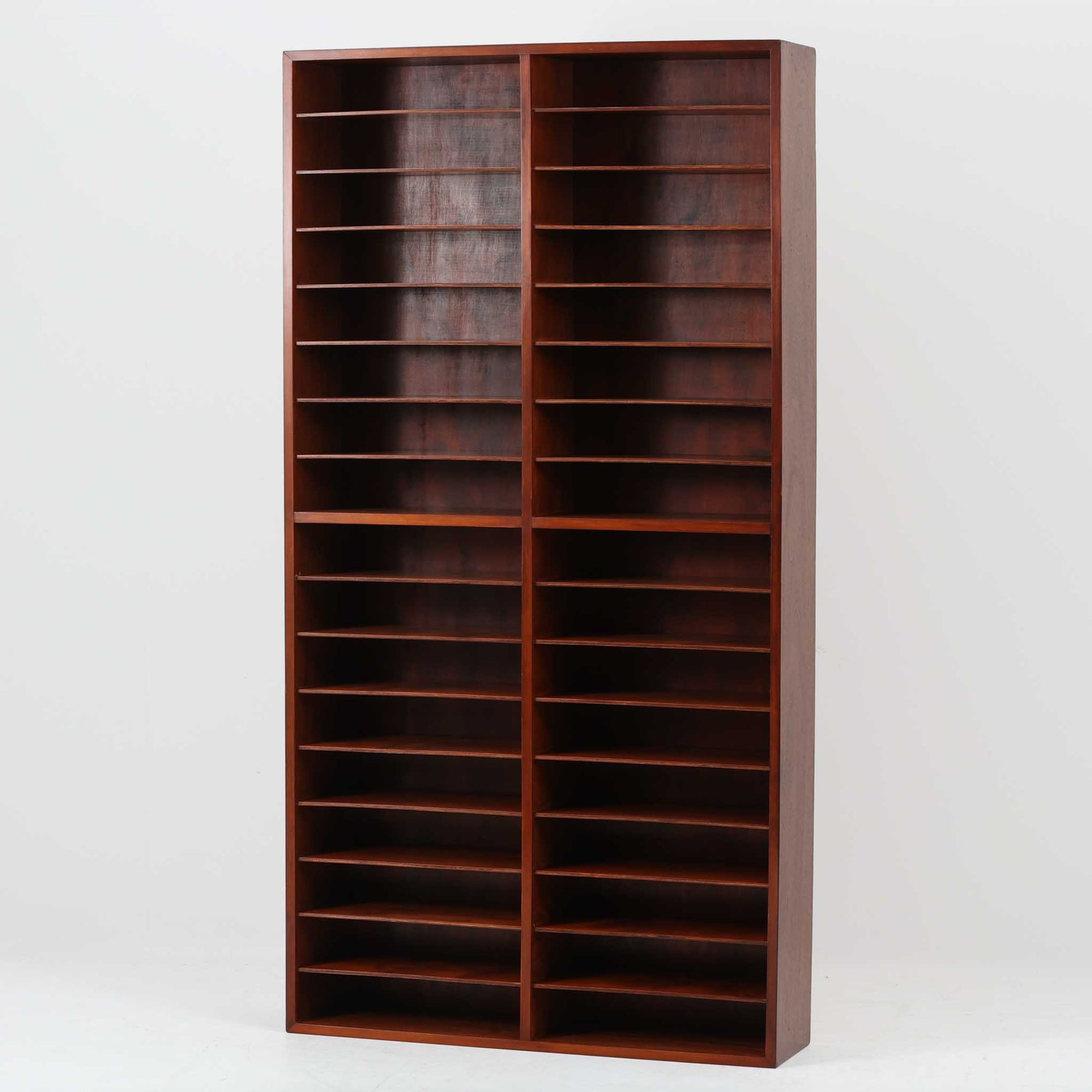 デンマーク製の書類収納シェルフです。ラワン材の深みある赤褐色の木肌を活かした端正な佇まいに、細かく区切られた棚構成が印象的で、A4書類や封筒、カタログなどを少し見せながら整然と仕分け収納できる実用性の高い一台です。縦長ながら圧迫感を抑えたすっきりとしたフォルムで、書斎やワークスペースはもちろん、ショップでの伝票整理や店舗什器としてもおすすめ。書類やペーパーアイテム、小物類を美しく並べることで、見せる収納として空間にリズムを生み出します。経年で増した木肌の艶とビンテージならではの味わいが、空間に落ち着いた存在感を添えます。