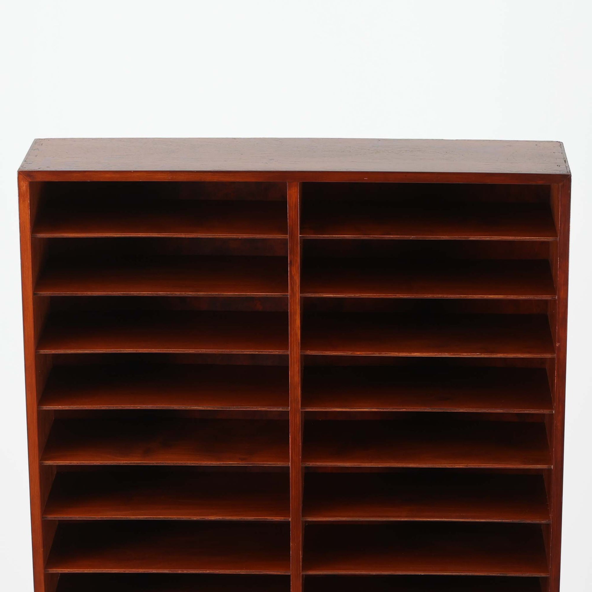 デンマーク製の書類収納シェルフです。ラワン材の深みある赤褐色の木肌を活かした端正な佇まいに、細かく区切られた棚構成が印象的で、A4書類や封筒、カタログなどを少し見せながら整然と仕分け収納できる実用性の高い一台です。縦長ながら圧迫感を抑えたすっきりとしたフォルムで、書斎やワークスペースはもちろん、ショップでの伝票整理や店舗什器としてもおすすめ。書類やペーパーアイテム、小物類を美しく並べることで、見せる収納として空間にリズムを生み出します。経年で増した木肌の艶とビンテージならではの味わいが、空間に落ち着いた存在感を添えます。