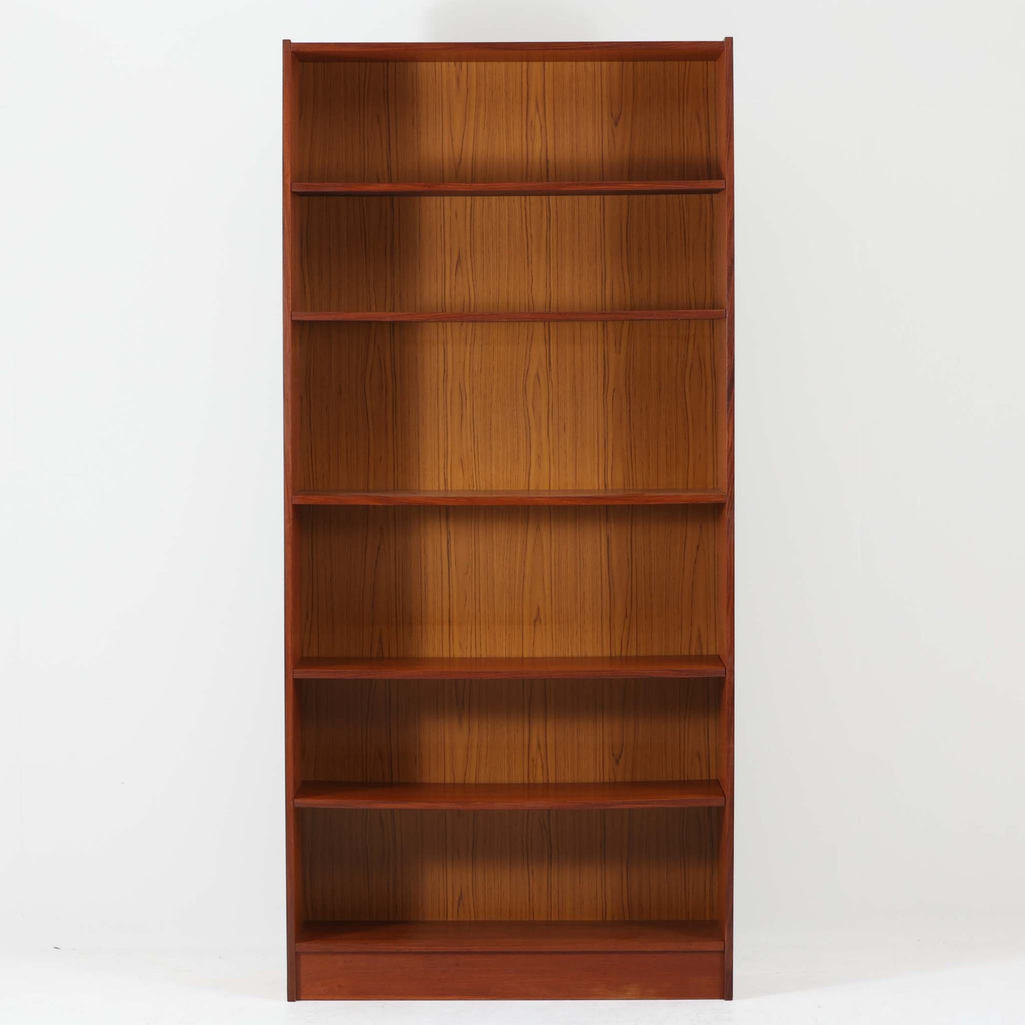 デンマーク製ブックシェルフです。チーク材の美しい木目と、経年で深みを増した飴色の表情が空間に上質な温もりを添える一台。高さを活かした縦長フォルムにバランスよく配置された棚板は、書籍や雑誌をたっぷり収納できるだけでなく、アートやオブジェを飾るディスプレイスペースとしても映えます。すっきりとしたシンプルな構造は圧迫感を抑え、リビングや書斎、ショップ什器にも取り入れやすいデザイン。背面はチークシート仕上げとなっており、壁付けはもちろん、空間の間仕切りとしても北欧らしい統一感を損なわずお使いいただけます。なお、棚板には約5mm程度のわずかな反りが見られますが、ご使用や見た目を大きく損なうものではなく、ビンテージ品ならではの風合いとしてお楽しみいただけるコンディションです。