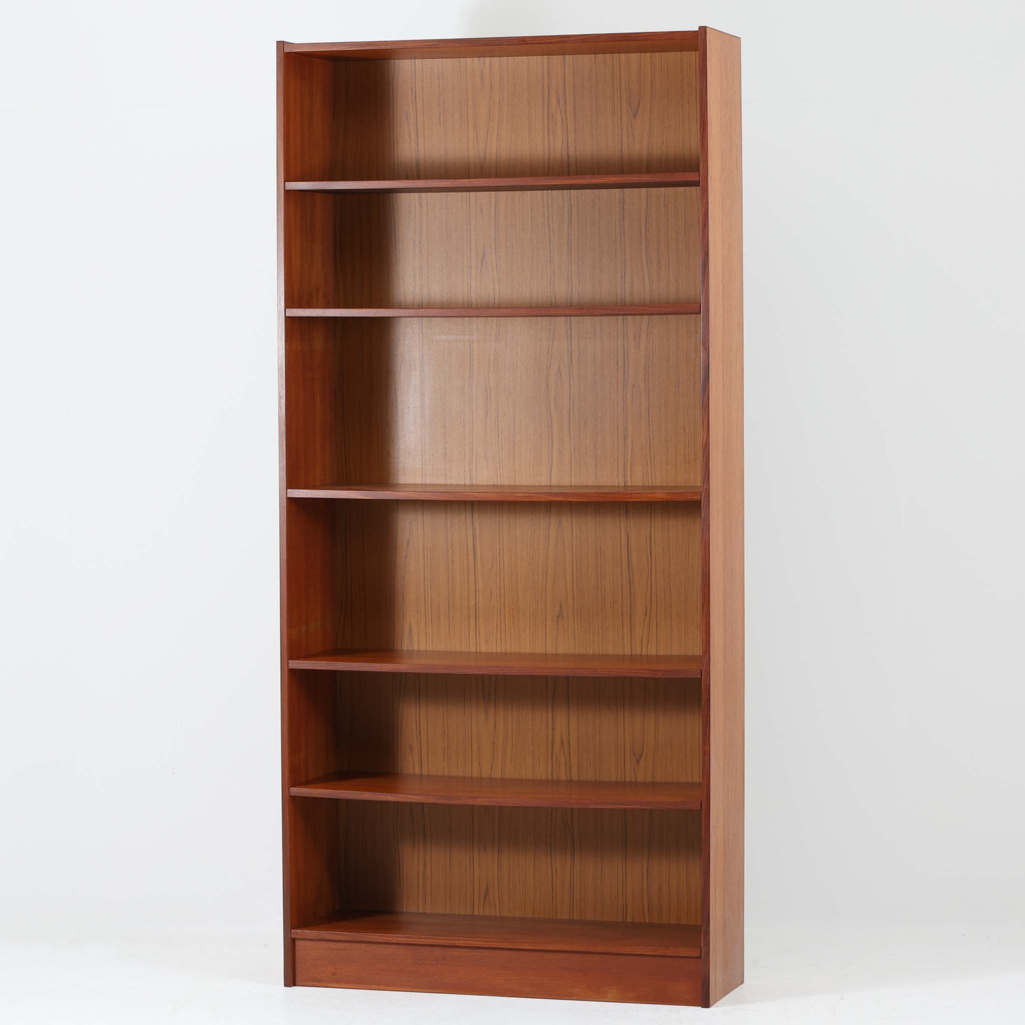 デンマーク製ブックシェルフです。チーク材の美しい木目と、経年で深みを増した飴色の表情が空間に上質な温もりを添える一台。高さを活かした縦長フォルムにバランスよく配置された棚板は、書籍や雑誌をたっぷり収納できるだけでなく、アートやオブジェを飾るディスプレイスペースとしても映えます。すっきりとしたシンプルな構造は圧迫感を抑え、リビングや書斎、ショップ什器にも取り入れやすいデザイン。背面はチークシート仕上げとなっており、壁付けはもちろん、空間の間仕切りとしても北欧らしい統一感を損なわずお使いいただけます。なお、棚板には約5mm程度のわずかな反りが見られますが、ご使用や見た目を大きく損なうものではなく、ビンテージ品ならではの風合いとしてお楽しみいただけるコンディションです。