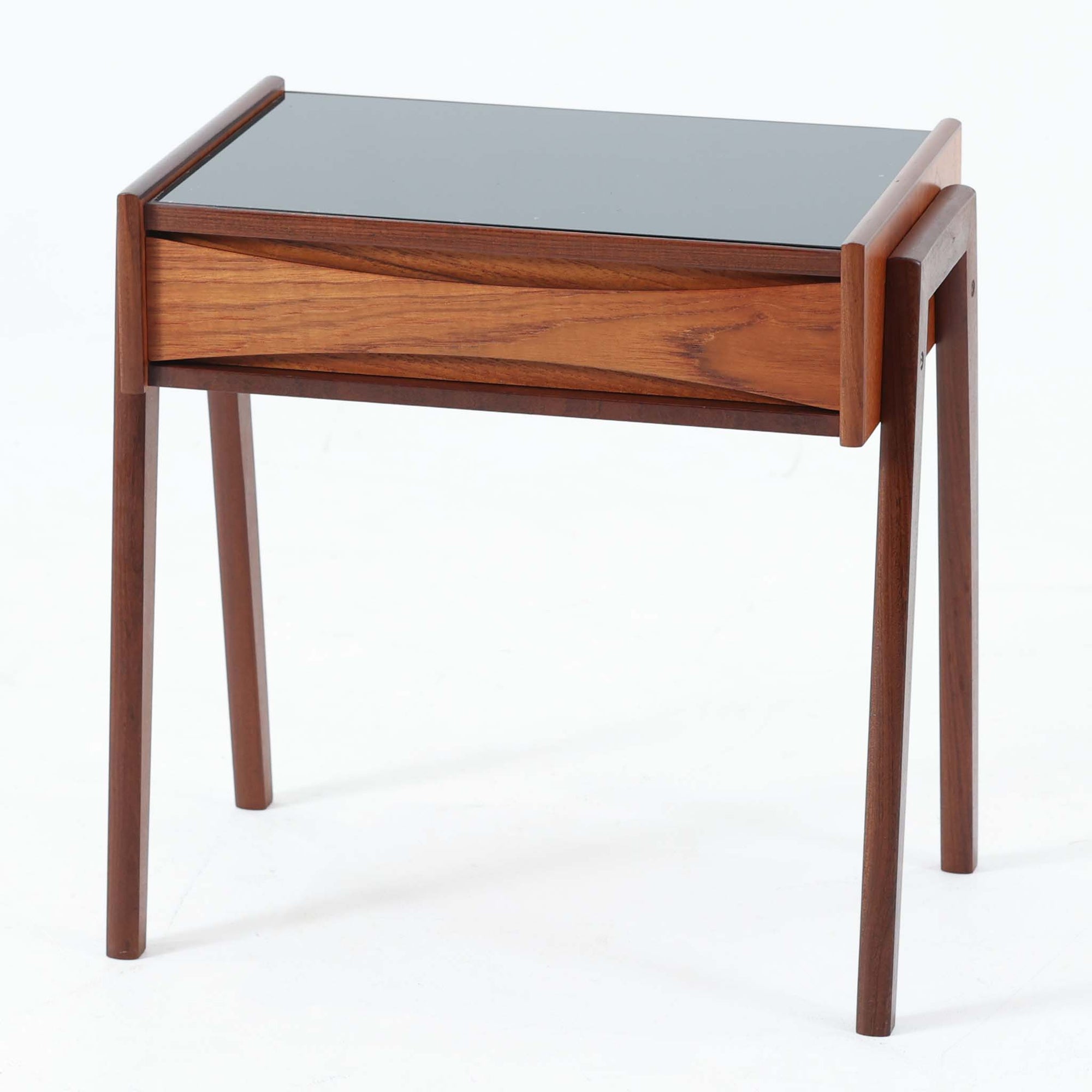 Arne Vodderがデザインし、Olholm Mobelfabrikで製作されたサイドテーブルです。温かみのある木部フレームと軽やかな印象の天板構成が美しく調和し、北欧らしい洗練された佇まいを演出します。曲線を描く幕板の意匠や丸みを帯びた脚部など、随所に職人技が感じられる丁寧なつくりも魅力。ソファ横やベッドサイドでの小物置きやランプ台として活躍し、経年により深みを増した素材感が空間に上質なアクセントを添えるビンテージ家具です。