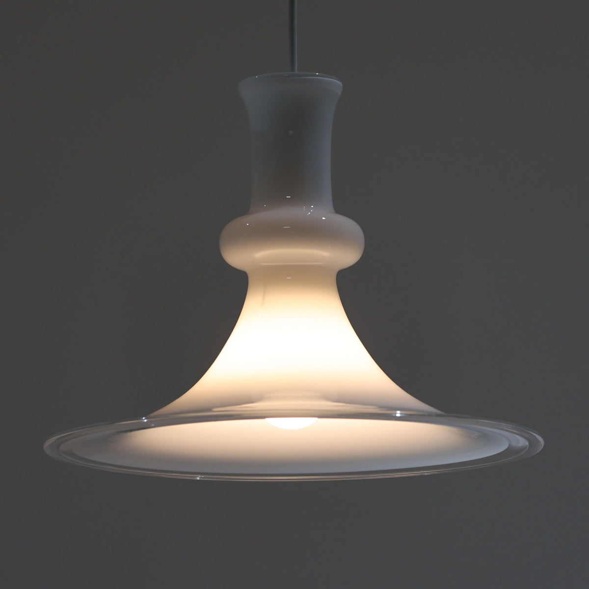 柔らかな曲線を描くガラスシェードが印象的な「Etude」のペンダントライトです。乳白色から透明へと移ろうガラスの表情が美しく、点灯時にはシェード全体に光が広がり、中央から裾にかけて穏やかなグラデーションを生み出します。直径38cmと存在感がありながら、軽やかで優美なフォルムが空間に自然と馴染み、ダイニングやリビングの主照明にもおすすめ。ガラスならではの繊細な質感と造形美を楽しめる北欧ビンテージ照明です。