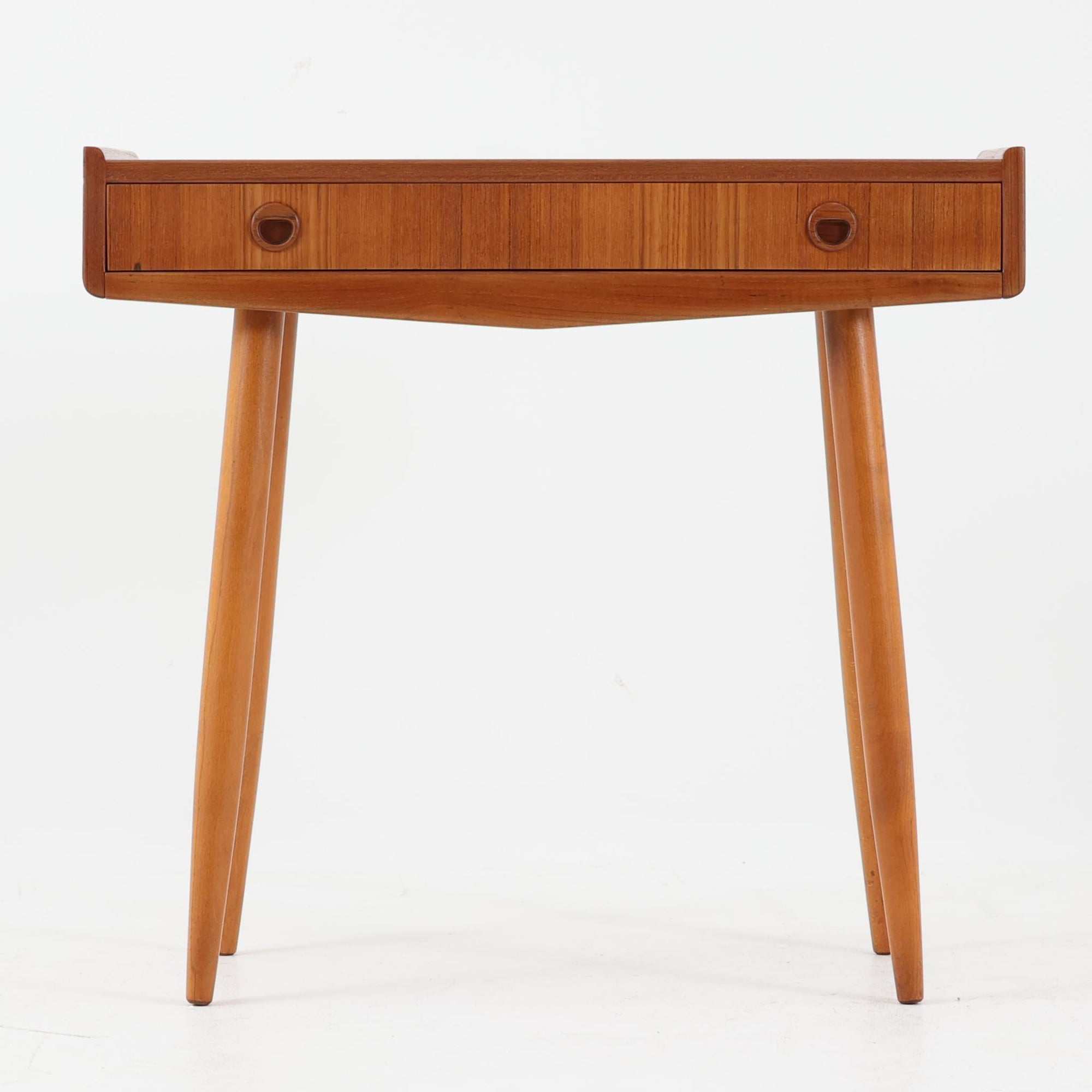 スウェーデン製のサイドチェストです。チーク材とビーチ材を組み合わせた温かみのある素材使いが特徴で、天板の立ち上がりや丸みを帯びた縁取りがやわらかな印象を与えます。前面には引き出しが備えられ、小物の整理に便利な実用性も魅力。すっきりと伸びたテーパー脚が軽やかさを添え、リビングやベッドサイド、玄関先など幅広いシーンで活躍します。経年により深みを増した木肌と丁寧な造りが、北欧ビンテージならではの落ち着いた存在感を演出する一台です。