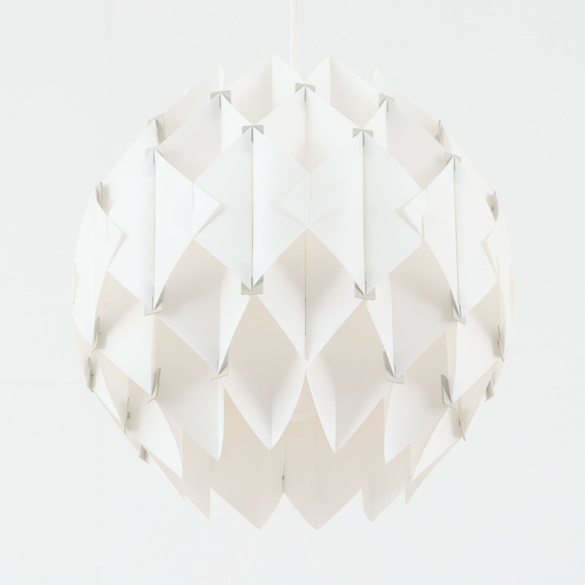 Lars Schiolerがデザインし、Hoyrupが手掛けたモデル「Butterfly」のペンダントライトです。プラスチックシートを幾何学的に組み合わせた立体構造が特徴で、点灯時には光と影が重なり合い美しい陰影を生み出します。軽やかな素材ながら彫刻的な存在感を持ち、空間のアクセントとして印象的に映える一灯。経年による風合いも相まって、北欧ビンテージならではのデザイン性と希少性を楽しめ、ダイニングやリビングに柔らかな雰囲気をもたらします。