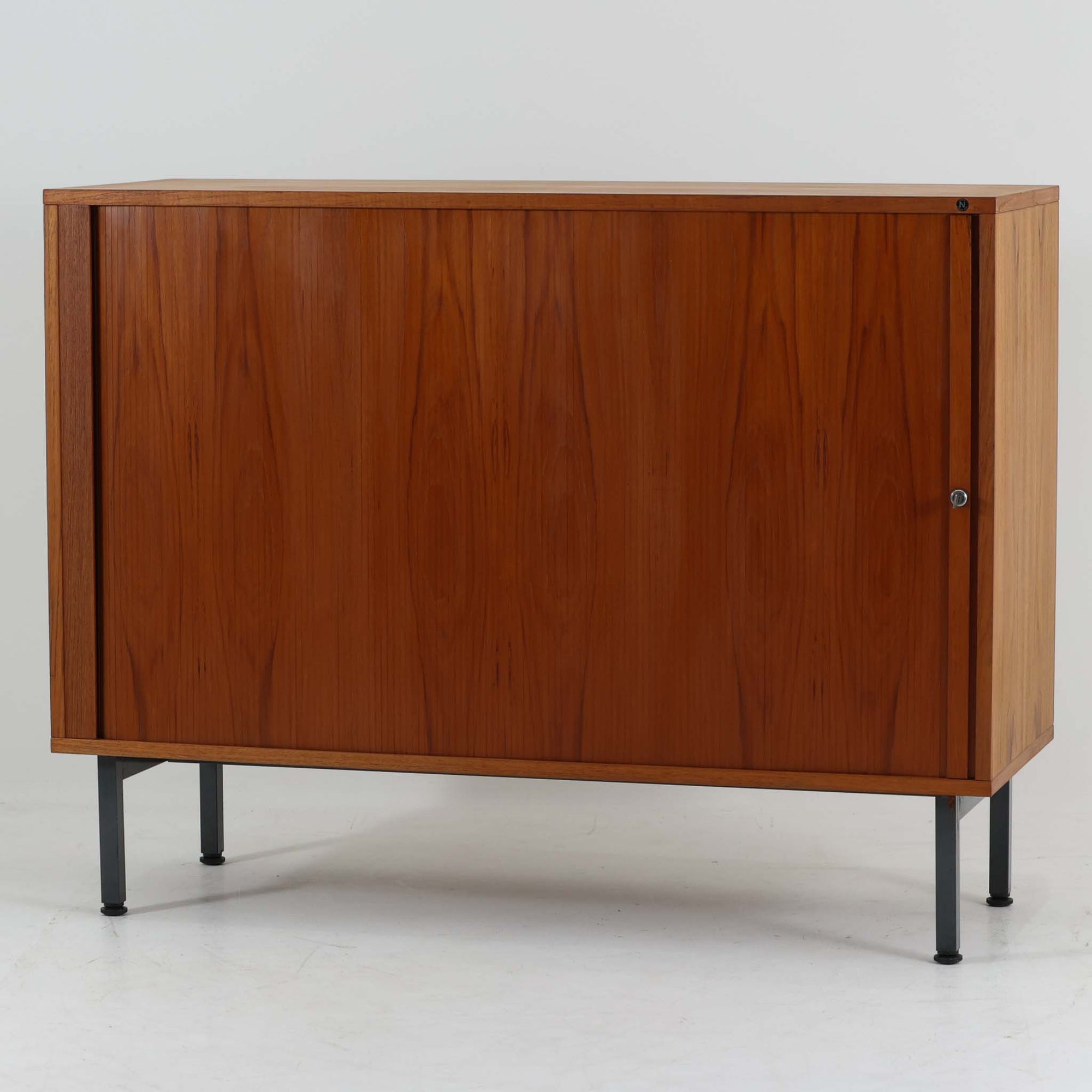 Marius Byrialsen（マリウス・ビリアルセン）デザイン、Nipu（ニプ）製のデンマーク製蛇腹キャビネットです。幅120cmの存在感あるサイズに、滑らかに開閉する蛇腹扉とシャープなスチール脚を組み合わせた、機能美あふれる一台。内部はオープンスペースと4マスの仕切り収納で構成され、レコードや書類、小物、オブジェを美しく整理できます。チーク材の流れるような木目と経年で深みを増した艶やかな木肌が、洗練された佇まいをより引き立て、リビングのサイドボードやワークスペースの収納家具としても活躍。デザイナー性の高い構造と希少な蛇腹機構が、北欧ビンテージならではの上質な存在感を空間にもたらします。