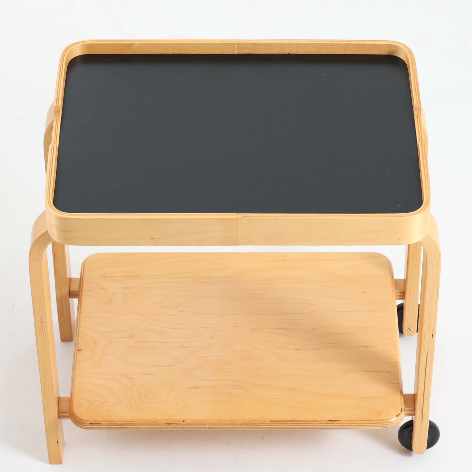 Carina Bengsがデザインし、IKEAで製作された「Brunabo」シリーズのキャスターワゴンです。バーチ材を使用した明るくやわらかな木目が特徴で、北欧らしいシンプルで温かみのあるデザインに仕上げられています。2000年代に製作されたモデルで、現在はすでに生産終了していると考えられ、ビンテージとして楽しめるアイテムです。上段は取り外し可能なトレイ仕様になっており、飲み物や小物を運ぶサービングトレイとしても使用できる実用的な構造。トレイを外した状態でも天板として使えるため、用途に応じた使い方が可能です。下段には棚板が設けられており、雑誌やキッチン用品、日用品などを収納できます。また片側のみにキャスターが付いた設計になっているため、一般的なワゴンよりも安定感があり、必要な時だけ持ち上げて移動できる使い勝手の良さも魅力。リビングやダイニング、キッチンなどさまざまな空間で活躍する、北欧らしい機能性とデザイン性を兼ね備えたワゴンです。