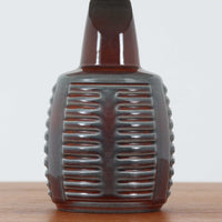 Rigmor Nielsenがデザインし、Soholm Keramikが手掛けたテーブルランプです。高さ37cmの取り入れやすいサイズに、艶やかな陶磁器ベースとナチュラルなリネンシェードを組み合わせた、落ち着きある北欧ビンテージらしい一台。ベースには規則的な立体リブ装飾が施され、陰影豊かな表情と彫刻的な存在感を生み出しています。点灯時にはシェード越しの柔らかな光が釉薬の奥行きや貫入の表情を引き立て、チェストやサイドテーブル、ベッドサイドに穏やかな雰囲気を演出。Rigmor Nielsenらしい造形美とSoholmの高い陶芸技術が感じられる、希少性の高いビンテージ照明です。