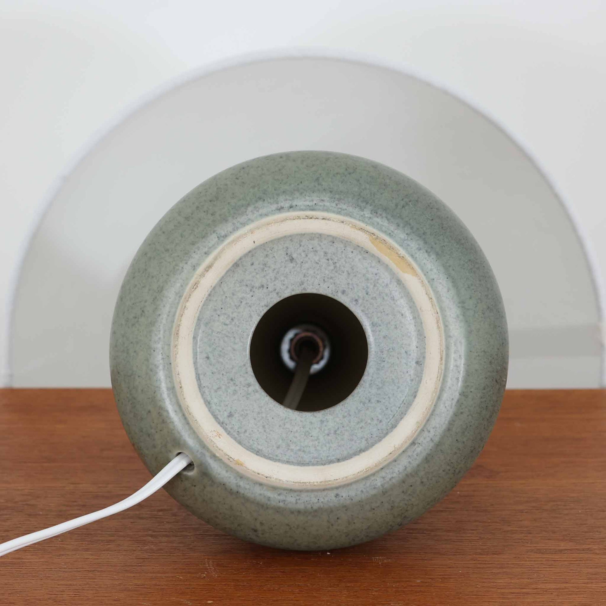 Einar Johansenがデザインし、Soholm Keramikが製作したモデル1028のテーブルランプです。高さ33cmの使いやすいサイズに、淡いセージグリーンの陶磁器ベースと上質なリネンシェードを組み合わせた、北欧らしい静かな佇まいが魅力。胴部にぐるりと施された幾何学的なレリーフ文様が美しい陰影を生み、点灯時にはやわらかな光とともに立体感がより際立ちます。チェストやサイドテーブル、ベッドサイドにも馴染みやすく、落ち着いた色調が空間にやさしい温もりを添える一台。Johansenならではの端正な造形とSoholmの高い陶芸技術を感じられる、希少性の高いビンテージ照明です。