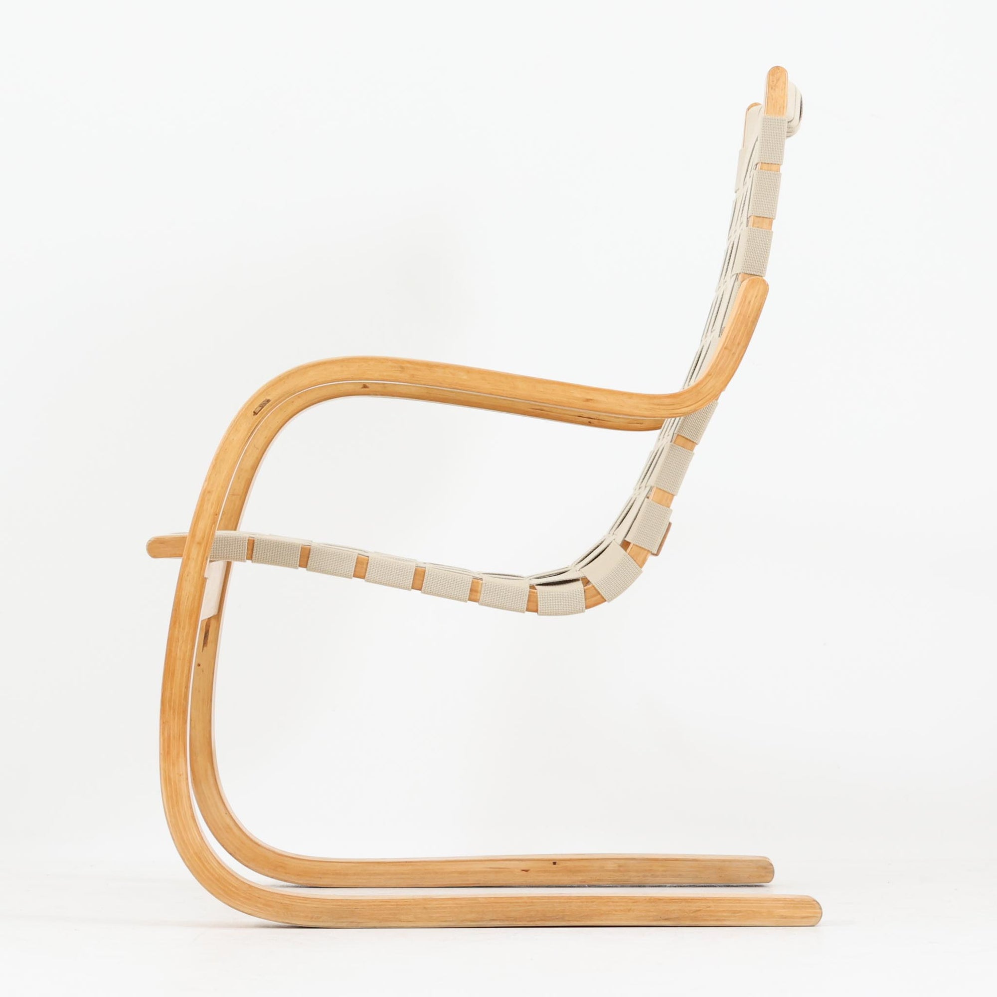 Alvar Aaltoが手掛けたARMCHAIR 406は、しなやかな曲線を描く成形バーチ材フレームが印象的な北欧モダンの名作です。アームから脚部へと流れる一体感のあるフォルムと、ウェビングテープを格子状に編み込んだ座面・背もたれが軽やかな存在感を演出します。身体を包み込むような柔軟性と快適な座り心地を備え、読書やラウンジスペースなどにも最適です。経年による風合いも魅力となり、機能性と造形美を兼ね備えた北欧ビンテージならではの価値を楽しめます。
