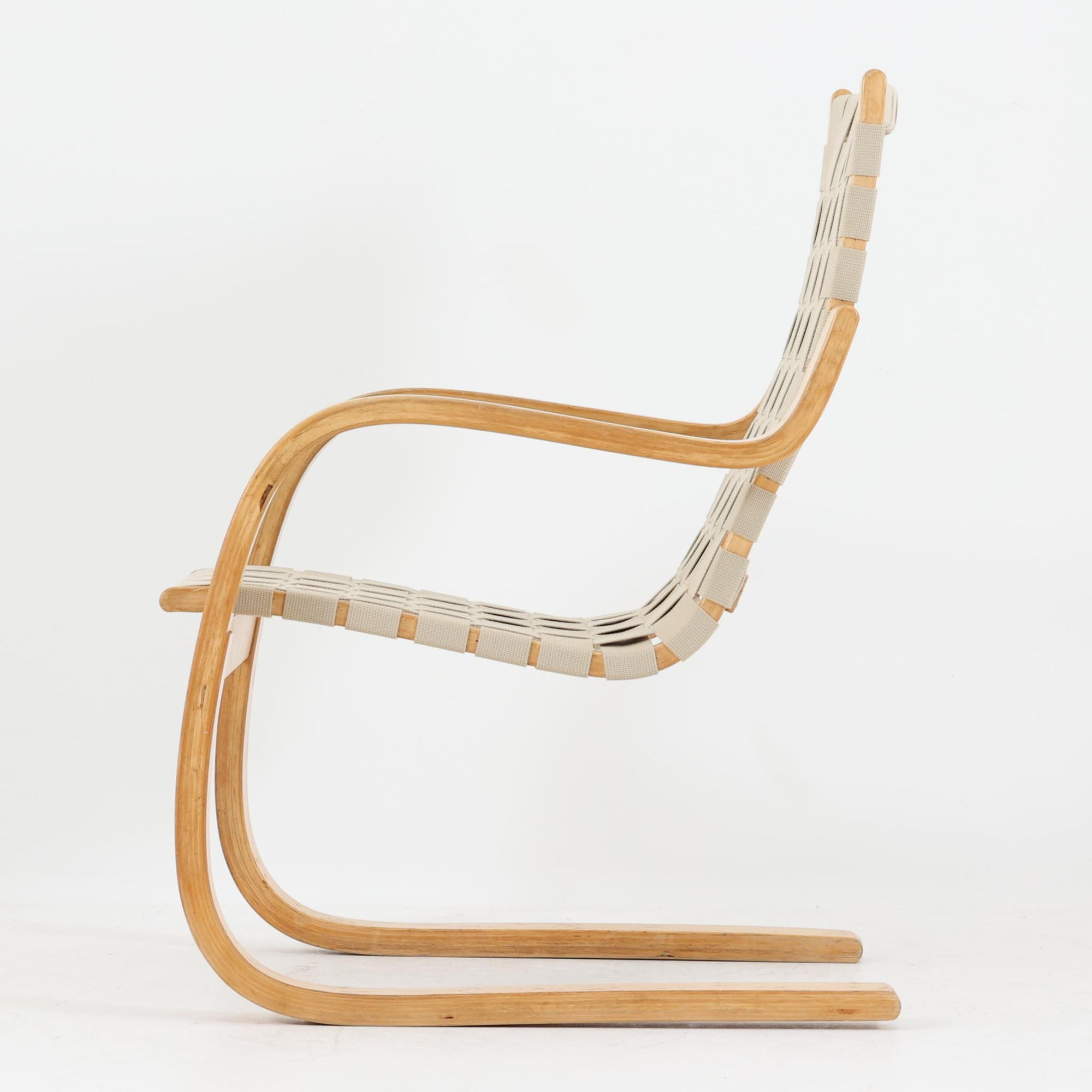 Alvar Aaltoが手掛けたARMCHAIR 406は、しなやかな曲線を描く成形バーチ材フレームが印象的な北欧モダンの名作です。アームから脚部へと流れる一体感のあるフォルムと、ウェビングテープを格子状に編み込んだ座面・背もたれが軽やかな存在感を演出します。身体を包み込むような柔軟性と快適な座り心地を備え、読書やラウンジスペースなどにも最適です。経年による風合いも魅力となり、機能性と造形美を兼ね備えた北欧ビンテージならではの価値を楽しめます。