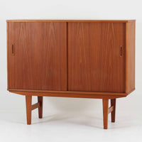 良質な木材を使用した本体は、美しい木目と経年により深みを増した色艶が魅力で、空間に落ち着いた存在感をもたらします。コンパクトなサイズ感ながら、引き戸内部には可動棚やトレイ収納を備え、食器や書類、小物を機能的に整理できる実用的な設計。すっきりとしたフォルムに対し、わずかに外側へ広がる脚部が軽やかさと安定感を両立し、ビンテージならではの丁寧な作りと佇まいを感じさせます。リビングやダイニングの収納家具としてはもちろん、ディスプレイ台としても活躍する一台です。