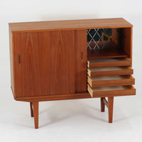 良質な木材を使用した本体は、美しい木目と経年により深みを増した色艶が魅力で、空間に落ち着いた存在感をもたらします。コンパクトなサイズ感ながら、引き戸内部には可動棚やトレイ収納を備え、食器や書類、小物を機能的に整理できる実用的な設計。すっきりとしたフォルムに対し、わずかに外側へ広がる脚部が軽やかさと安定感を両立し、ビンテージならではの丁寧な作りと佇まいを感じさせます。リビングやダイニングの収納家具としてはもちろん、ディスプレイ台としても活躍する一台です。