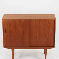 良質な木材を使用した本体は、美しい木目と経年により深みを増した色艶が魅力で、空間に落ち着いた存在感をもたらします。コンパクトなサイズ感ながら、引き戸内部には可動棚やトレイ収納を備え、食器や書類、小物を機能的に整理できる実用的な設計。すっきりとしたフォルムに対し、わずかに外側へ広がる脚部が軽やかさと安定感を両立し、ビンテージならではの丁寧な作りと佇まいを感じさせます。リビングやダイニングの収納家具としてはもちろん、ディスプレイ台としても活躍する一台です。