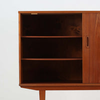 良質な木材を使用した本体は、美しい木目と経年により深みを増した色艶が魅力で、空間に落ち着いた存在感をもたらします。コンパクトなサイズ感ながら、引き戸内部には可動棚やトレイ収納を備え、食器や書類、小物を機能的に整理できる実用的な設計。すっきりとしたフォルムに対し、わずかに外側へ広がる脚部が軽やかさと安定感を両立し、ビンテージならではの丁寧な作りと佇まいを感じさせます。リビングやダイニングの収納家具としてはもちろん、ディスプレイ台としても活躍する一台です。