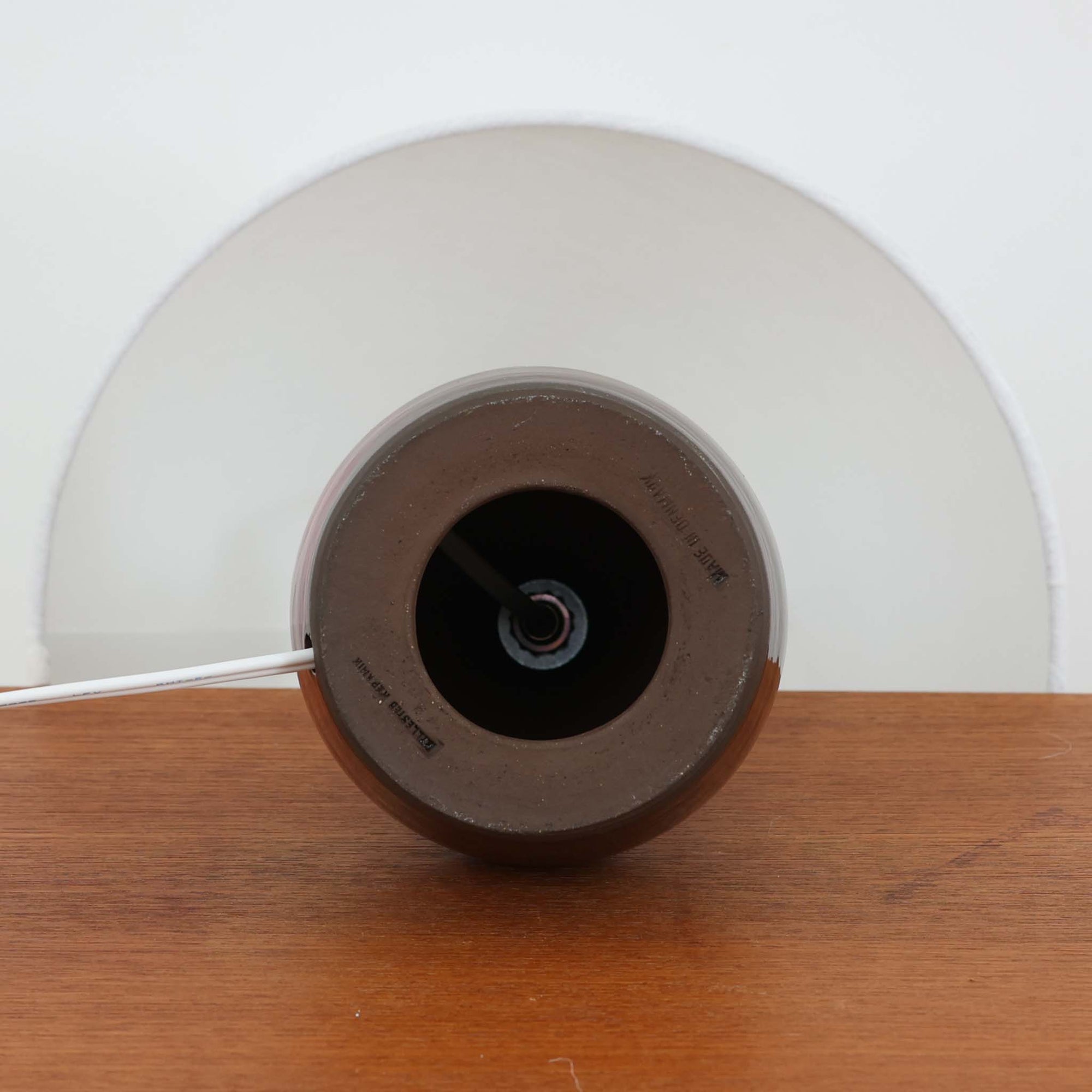 Hyllested Keramikによるデンマーク製ビンテージのテーブルランプです。深みのある赤褐色の陶磁器ベースは、丸みを帯びたボトルのような優美なフォルムと、釉薬の濃淡による豊かな表情が魅力。艶やかな質感の中に経年変化による味わいが重なり、空間に落ち着きと温もりを添えてくれます。すっきりとしたリネンシェードとの組み合わせが北欧らしい上品さを引き立て、リビングのサイドテーブルやベッドサイド、チェスト上のアクセント照明としてもおすすめ。メーカーならではの丁寧な焼成技術が感じられる、存在感のある一台です。