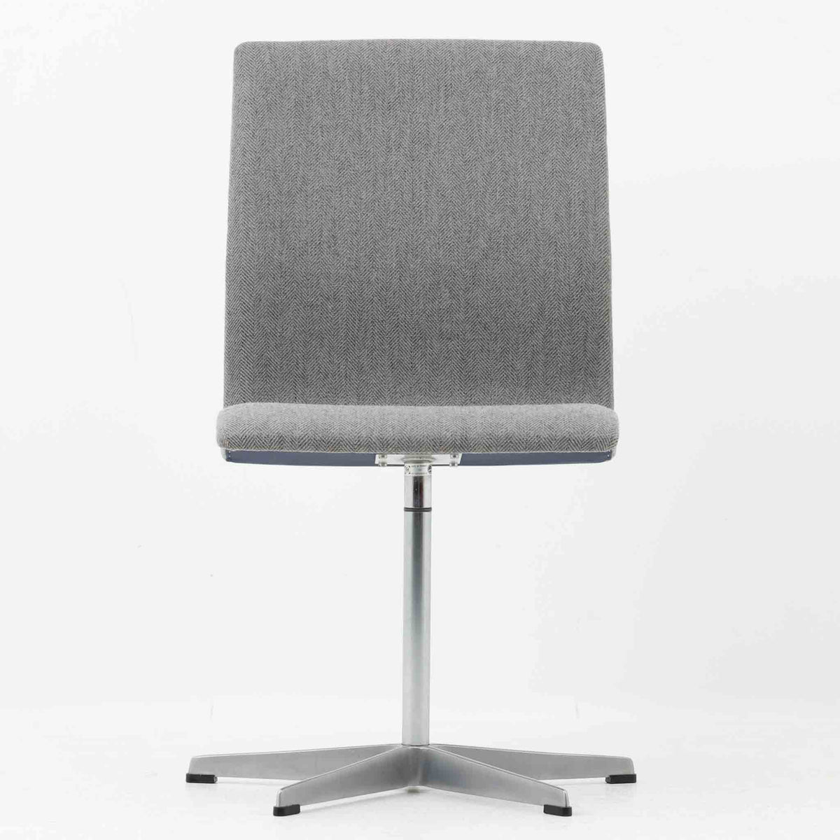 Arne Jacobsen（アルネ・ヤコブセン）がデザインし、Fritz Hansen（フリッツ・ハンセン）が製造したOxfordデスクチェアです。背から座面へ滑らかにつながる一体感のあるシートと、中央の支柱から伸びる端正な5本脚が、軽快で洗練された佇まいを演出しています。張地の落ち着いた表情と金属製ベースの組み合わせも美しく、書斎やワークスペース、ダイニングなど幅広い空間に取り入れやすい一脚。時代を超えて楽しめる端正な造形に、北欧ビンテージならではの存在感が感じられます。
