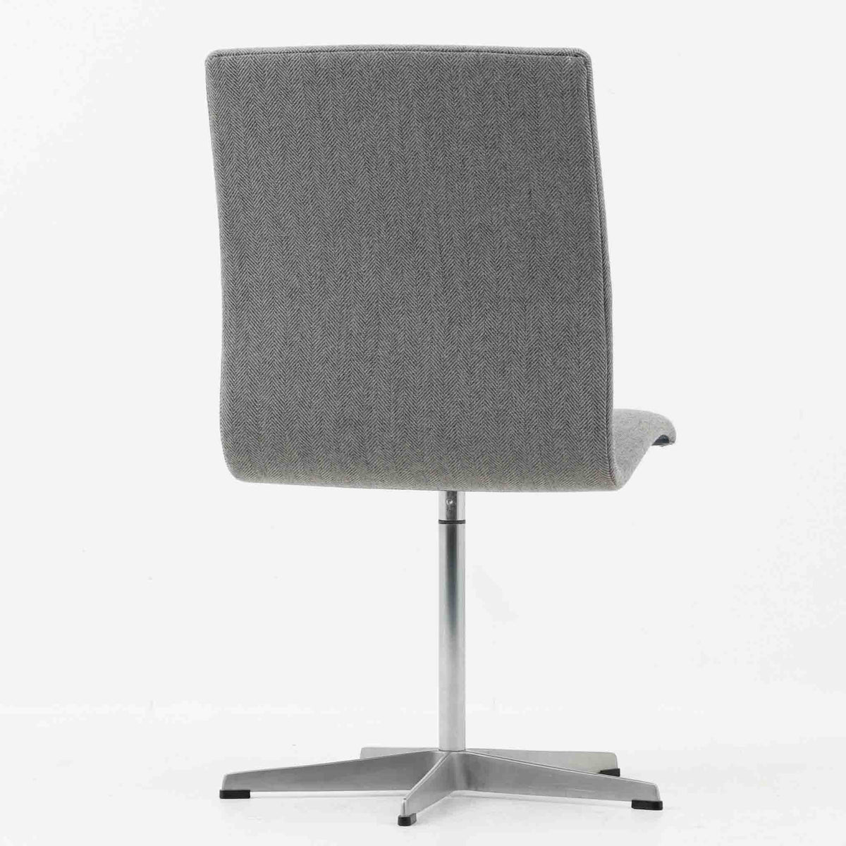 Arne Jacobsen（アルネ・ヤコブセン）がデザインし、Fritz Hansen（フリッツ・ハンセン）が製造したOxfordデスクチェアです。背から座面へ滑らかにつながる一体感のあるシートと、中央の支柱から伸びる端正な5本脚が、軽快で洗練された佇まいを演出しています。張地の落ち着いた表情と金属製ベースの組み合わせも美しく、書斎やワークスペース、ダイニングなど幅広い空間に取り入れやすい一脚。時代を超えて楽しめる端正な造形に、北欧ビンテージならではの存在感が感じられます。