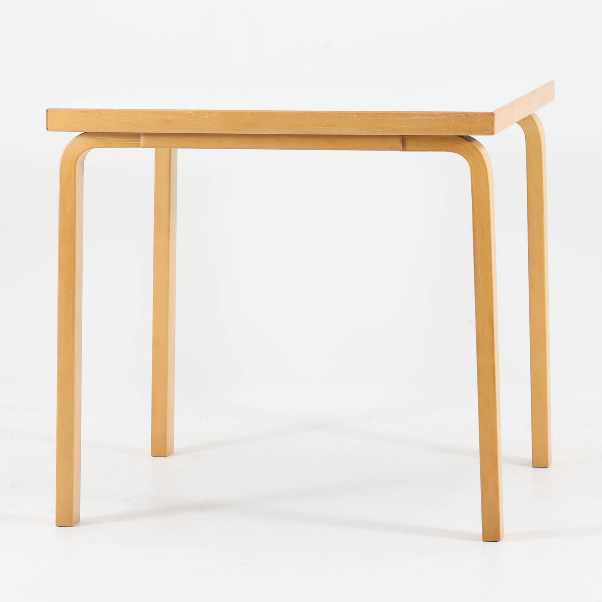 Alvar Aaltoがデザインし、Artekが製作したモデル81Cの正方形ダイニングテーブルです。バーチ材のしなやかな曲木脚とホワイトラミネート天板の組み合わせが、アアルトらしい機能美と軽やかな佇まいを生み出しています。幅75cmの扱いやすいサイズは2人用のダイニングテーブルとしてはもちろん、ワークデスクやショップ什器としても取り入れやすい一台。経年により深みを増した木肌と、長年使い込まれた天板の風合いがビンテージならではの味わいを感じさせ、Artekの普遍的なデザイン性と希少な北欧オリジナルの存在感を空間に添えてくれます。