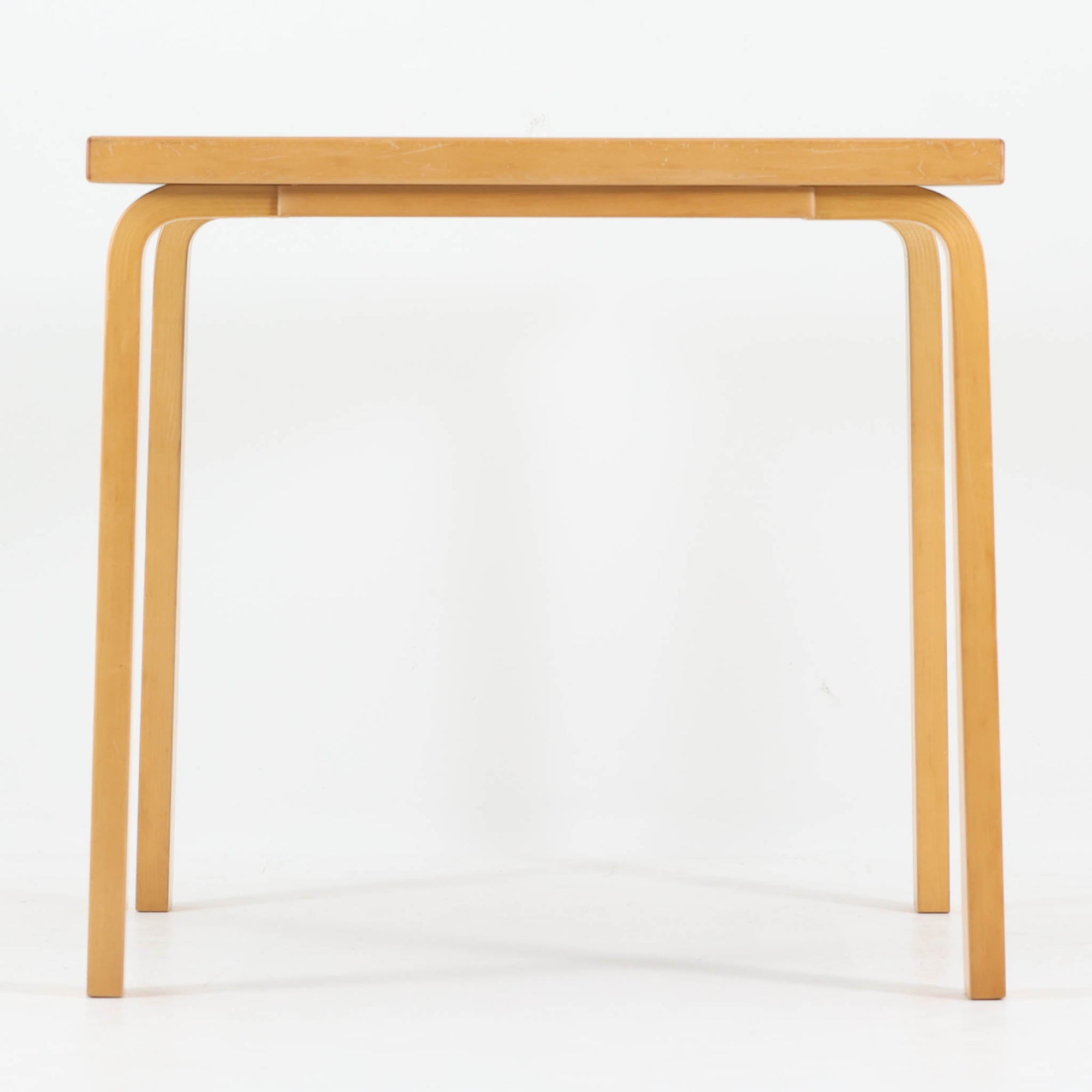 Alvar Aaltoがデザインし、Artekが製作したモデル81Cの正方形ダイニングテーブルです。バーチ材のしなやかな曲木脚とホワイトラミネート天板の組み合わせが、アアルトらしい機能美と軽やかな佇まいを生み出しています。幅75cmの扱いやすいサイズは2人用のダイニングテーブルとしてはもちろん、ワークデスクやショップ什器としても取り入れやすい一台。経年により深みを増した木肌と、長年使い込まれた天板の風合いがビンテージならではの味わいを感じさせ、Artekの普遍的なデザイン性と希少な北欧オリジナルの存在感を空間に添えてくれます。