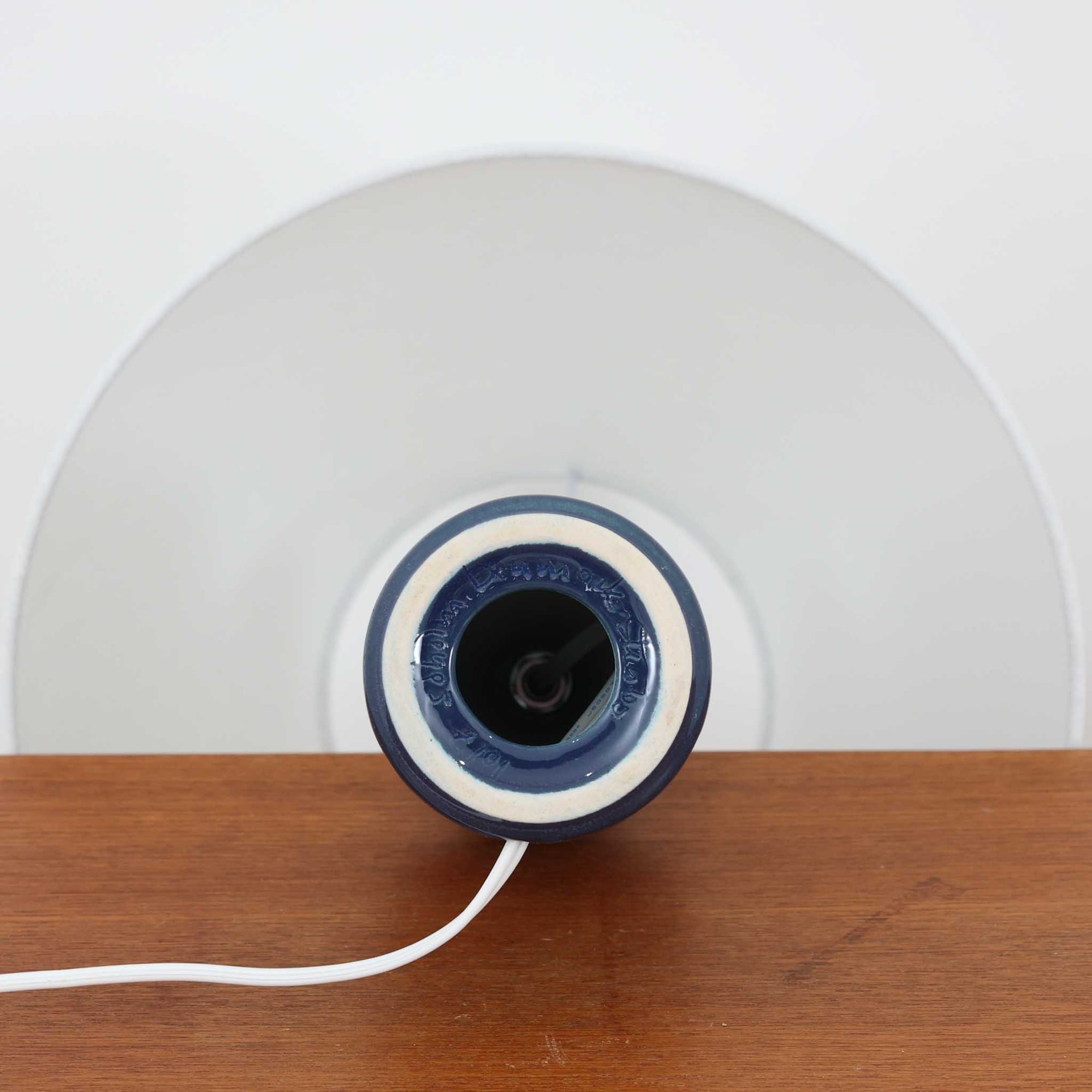 Soholm Keramikのモデル1017、Einar Johansenデザインによるデンマーク製ビンテージテーブルランプです。落ち着いた深いコバルトブルーの陶磁器ベースに、規則正しく並ぶ幾何学的なレリーフが美しい陰影を描き、静かな存在感を放つ一台。エイナー・ヨハンセンらしい端正で建築的なフォルムと、スーホルムならではの艶やかな釉薬表現が魅力です。リネンシェードを通した柔らかな灯りが立体的な意匠をより引き立て、サイドテーブルやチェスト、ベッドサイドに北欧らしい洗練された空気感を添えます。希少なモデルならではのコレクション性と、経年で深みを増した陶肌の味わいも楽しめます。